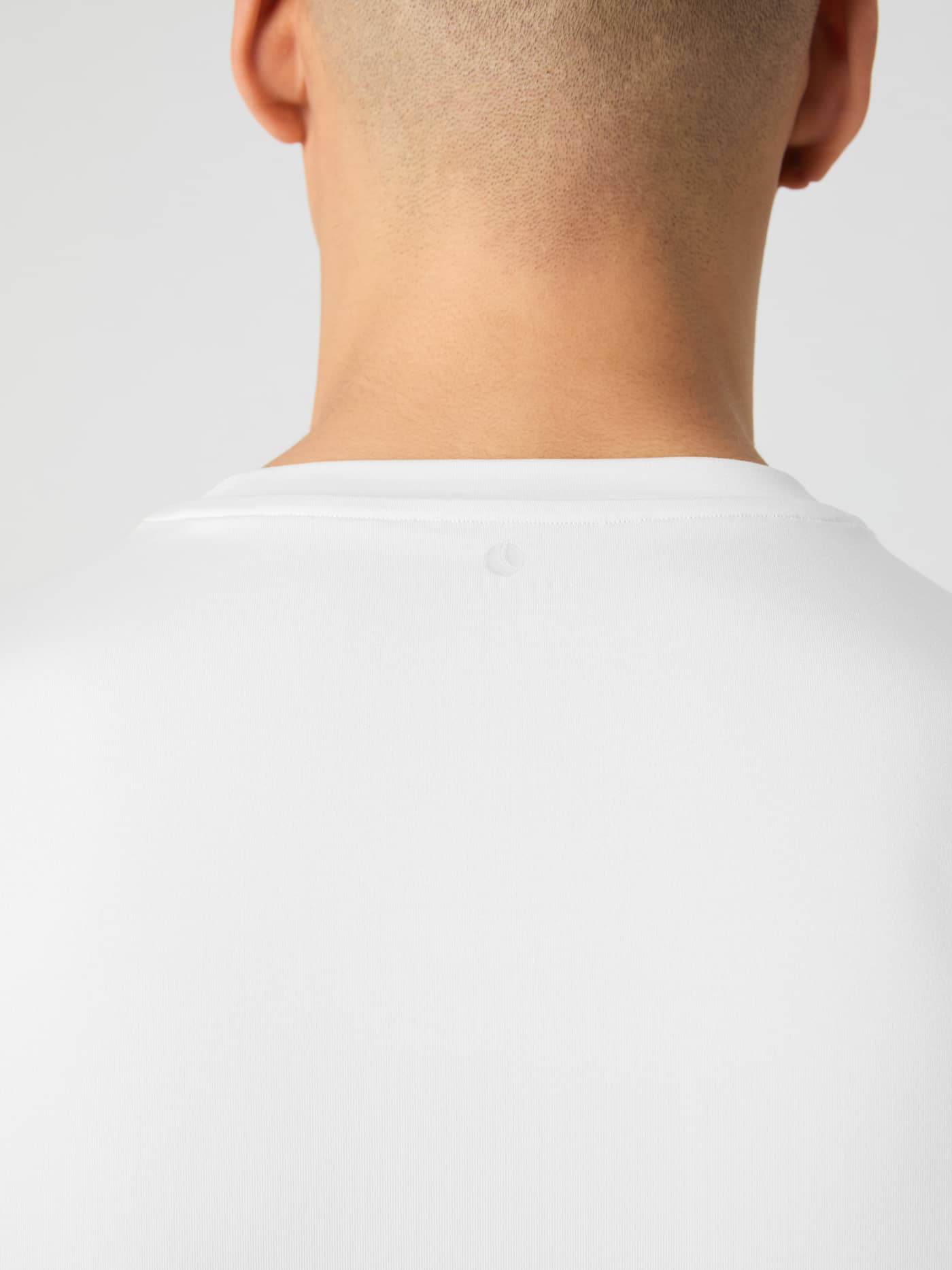 Back view of a model wearing the brilliant white Borg T-shirt, with a close-up on the neckline detail. - Image 4