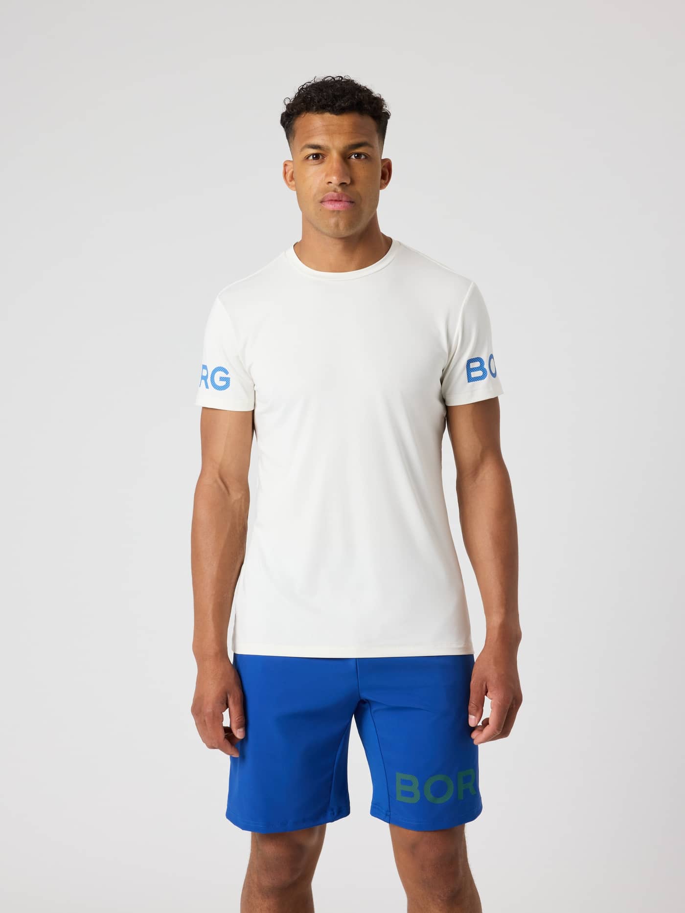 Front view of a man wearing the Tofu (white) Borg T-Shirt, a performance training tee with blue logos on the sleeves. - Image 1