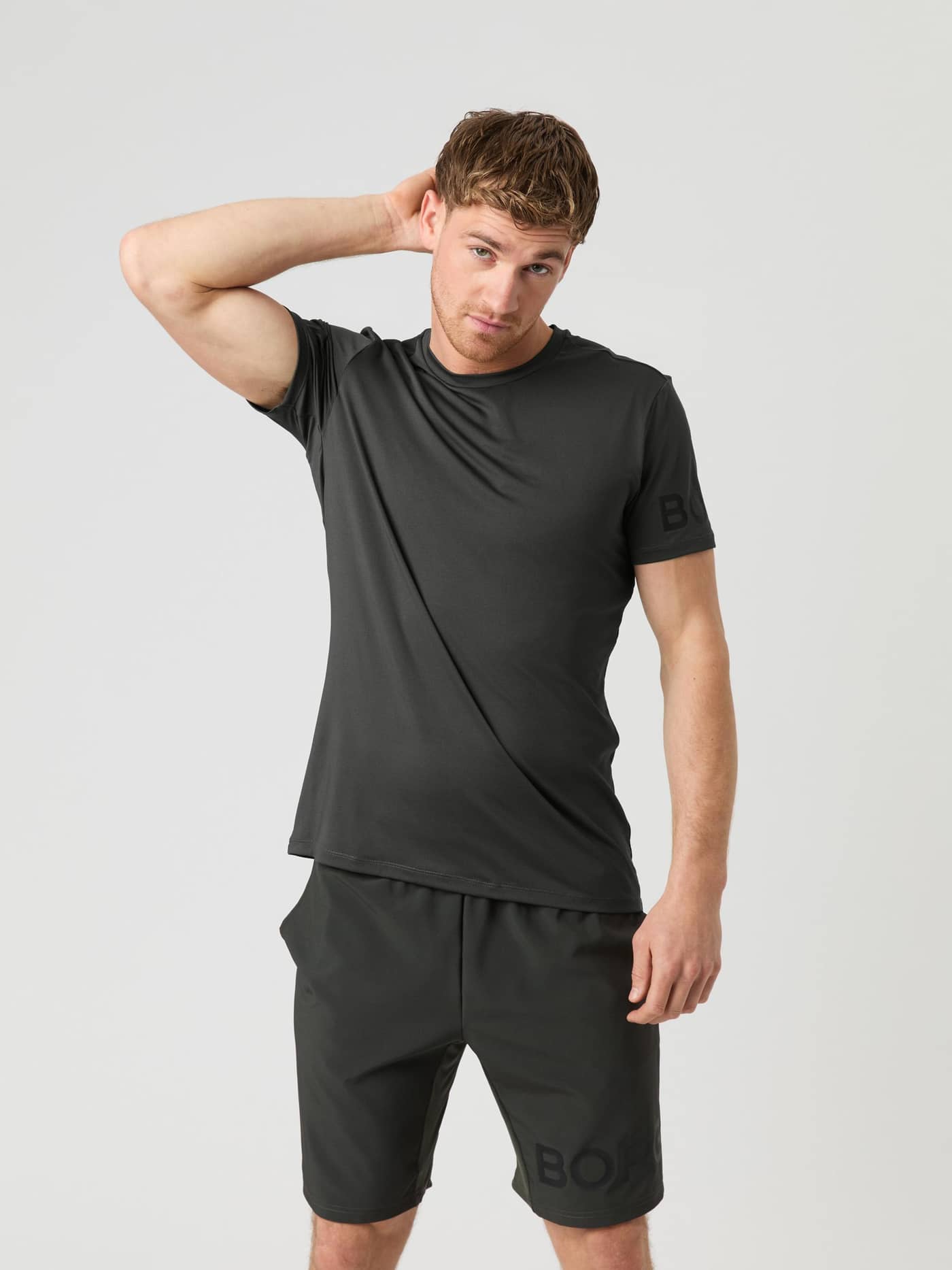 Front view of a male model wearing the peat green Björn Borg Borg T-shirt with matching shorts. - Image 1