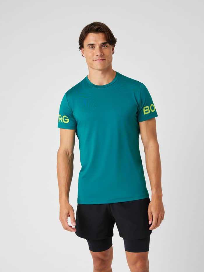 A male model faces forward wearing the Björn Borg Borg T-Shirt in Shaded Spruce green with black training shorts. - Image 4