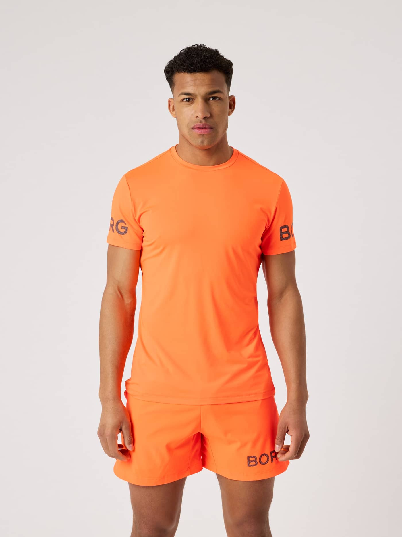 Front view of a man wearing the Björn Borg T-Shirt in Shocking Orange (Orange) for performance training. - Image 1