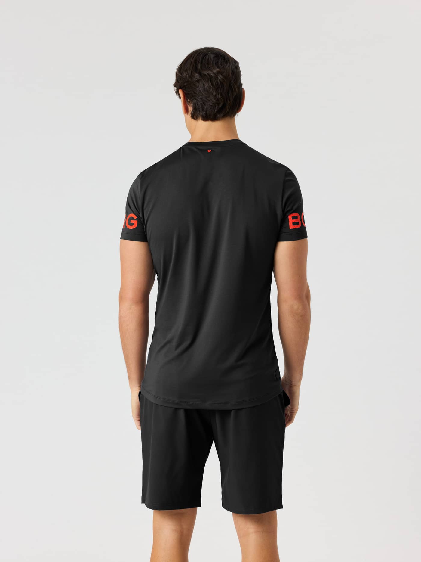 Vue arrière d'un modèle en Borg T-Shirt Black Orange Logo (Noir) avec logos orange sur les manches pour le training. - Image 3