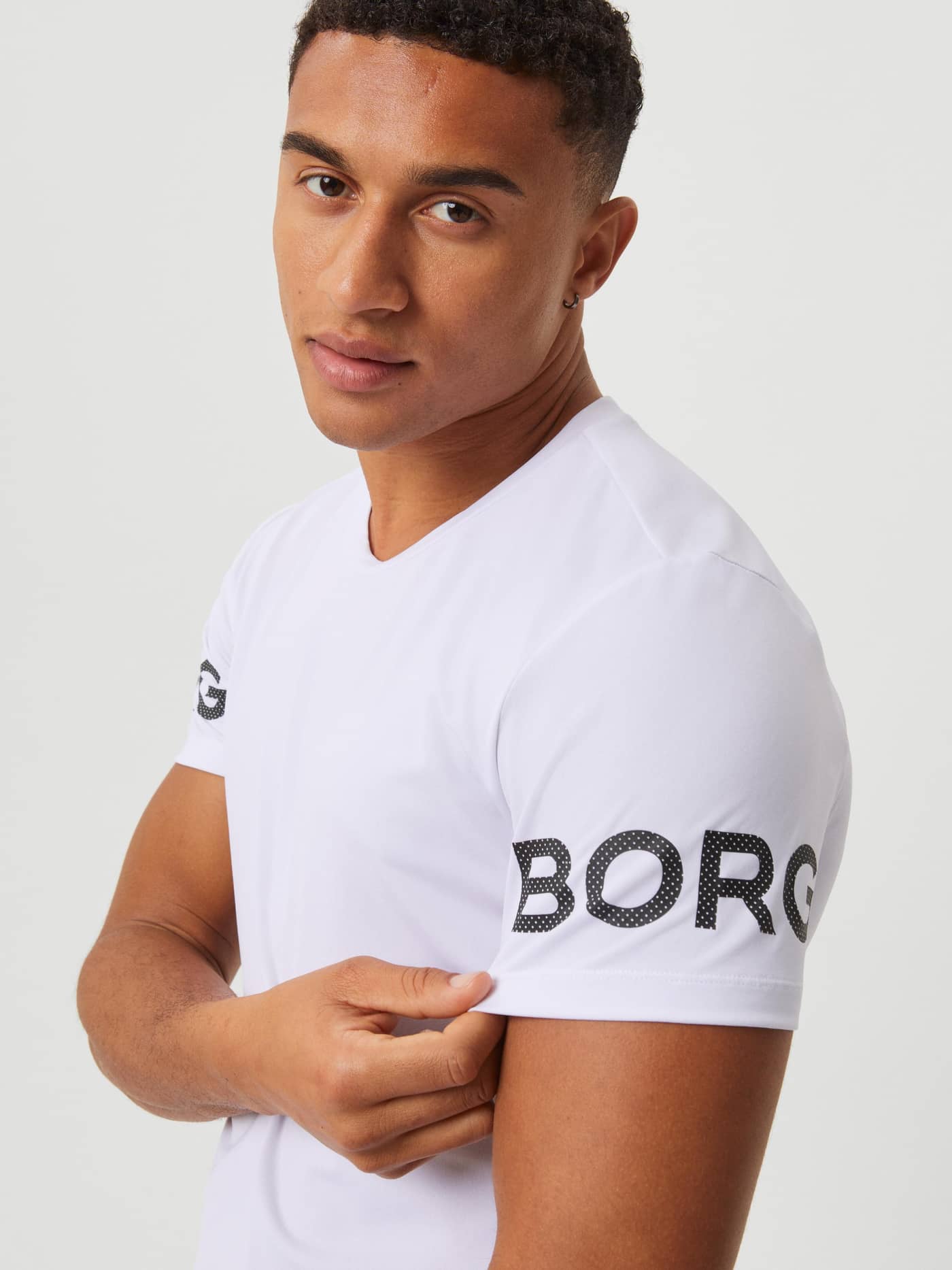 Närbild på Borg T-Shirt i White Black Logo (Vit) med en svart perforerad logotyp på ärmen för träning och tennis. - Image 4