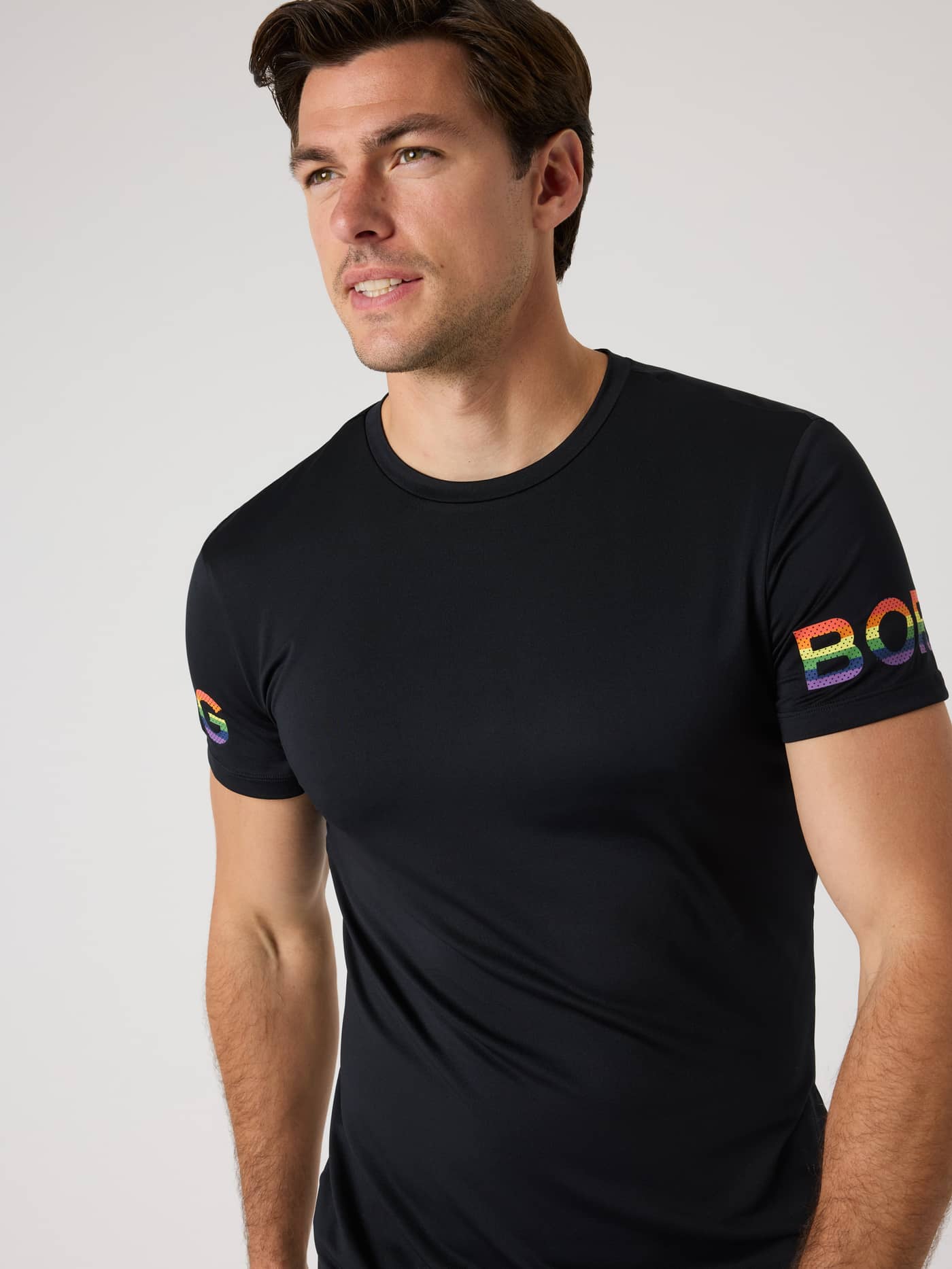 Vorderansicht eines Mannes im elastischen Borg T-Shirt in Black Beauty (Schwarz) für Training mit Regenbogen-Ärmellogos. - Image 2