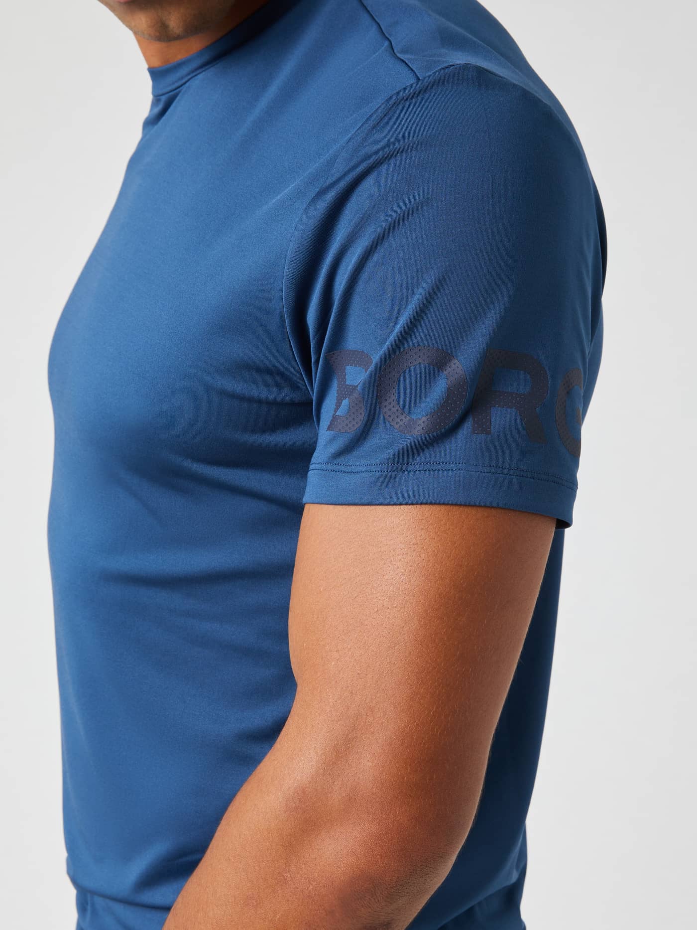 Seitenansicht eines Mannes im Borg T-Shirt in Sargasso Sea (Blau) für Training und Tennis mit dunklem Logo am Ärmel. - Image 5