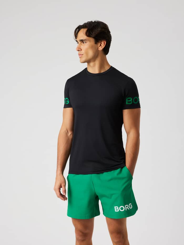 Male model wearing the Borg T-Shirt in Black Beauty (black) with green logo prints on the arms for training.