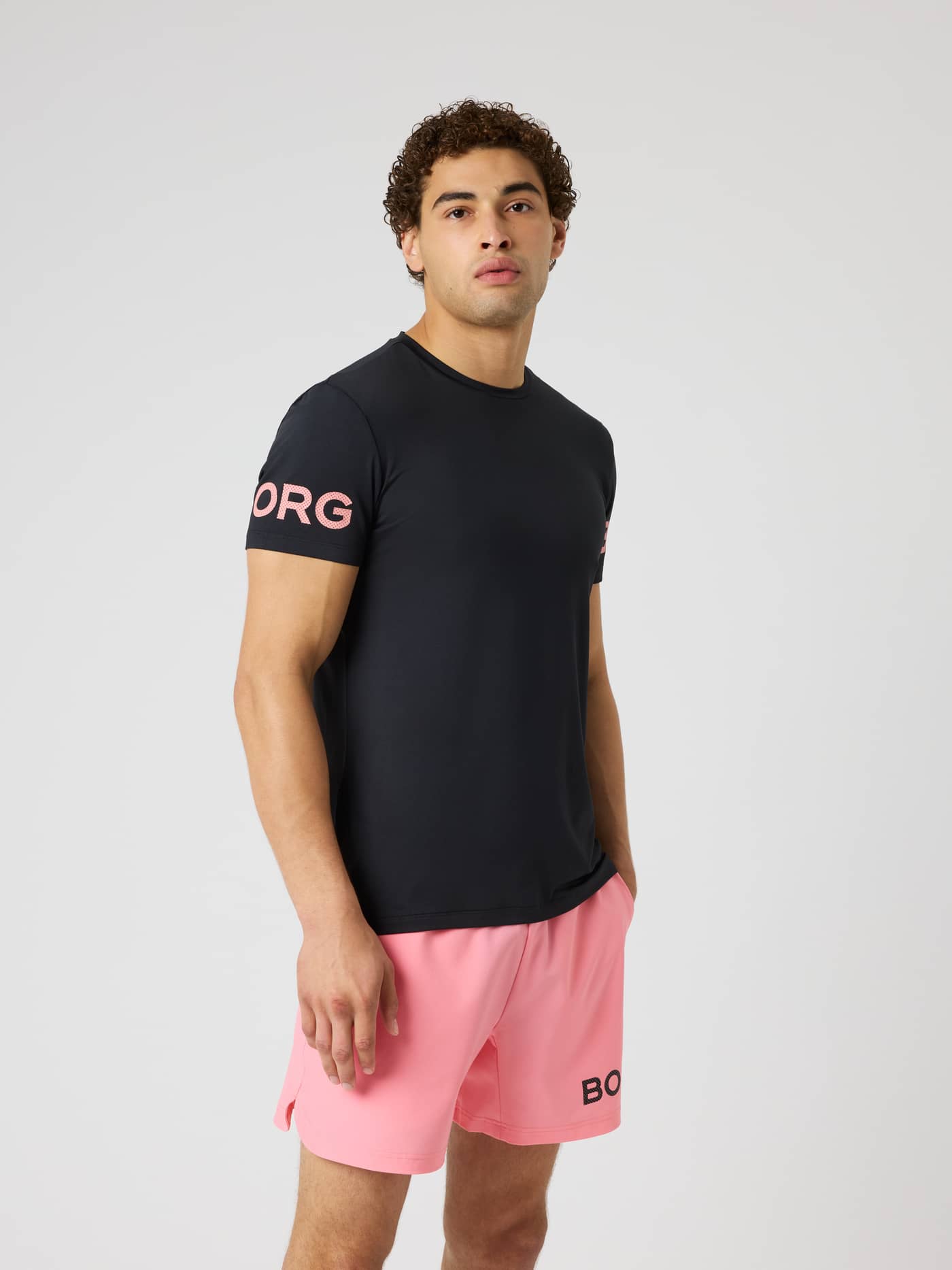 Vue de face d'un modèle en Borg T-Shirt Black Pink Logo (Noir) avec logos roses pour le training et le tennis. - Image 2