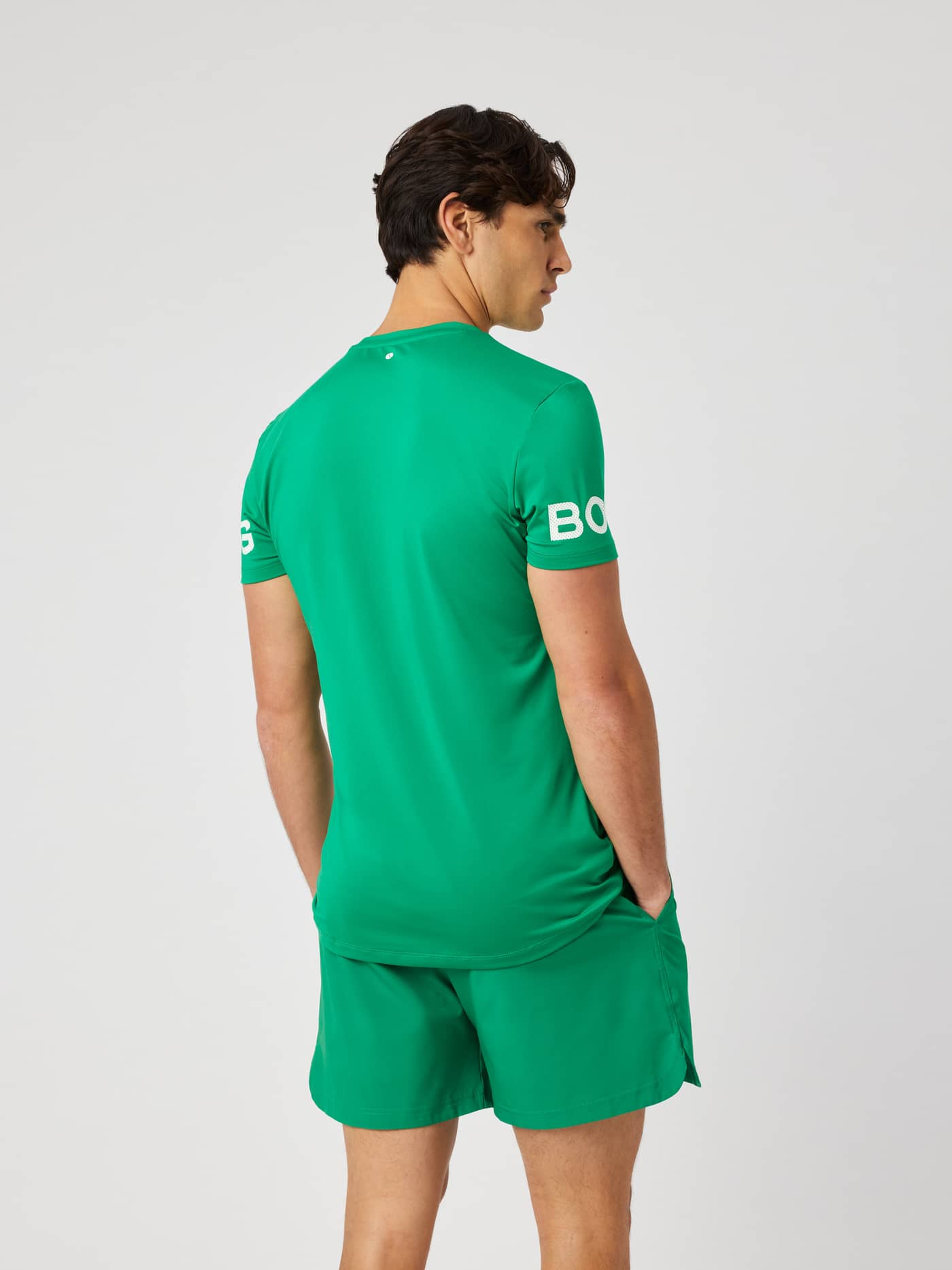 Back view of a man wearing the Borg T-Shirt in Jolly Green (green) for training, highlighting the white logo on the arms. - Image 3