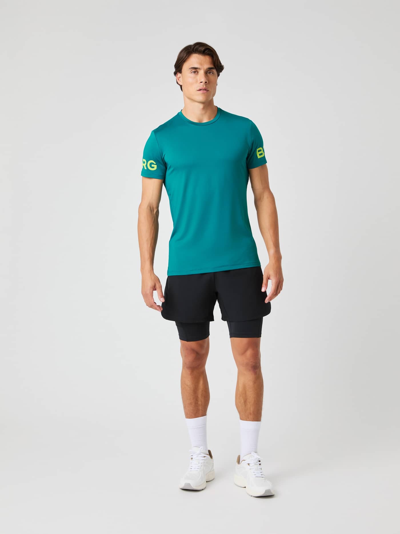 Front view of a male model wearing the Borg T-Shirt in Shaded Spruce, styled with black shorts. - Image 6