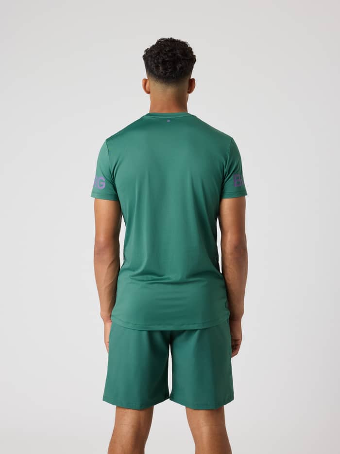 Rückansicht des Borg T-Shirt in Mallard Green (Grün) mit lila Logos, ein Performance-Trainingsoberteil mit längerem Rücken. - Image 2