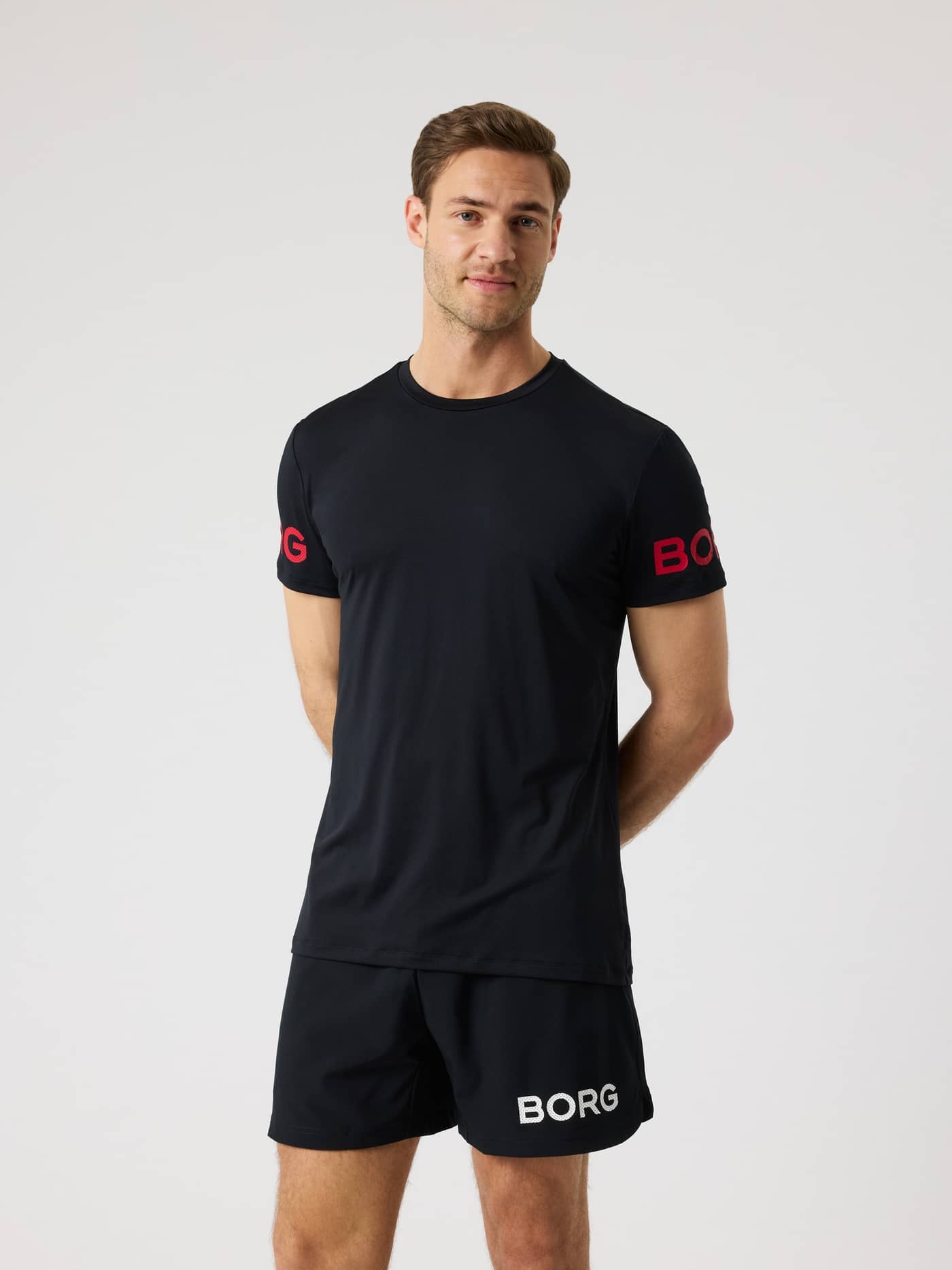 Front view of a man wearing the Borg T-Shirt in Black Beauty (Black) with red sleeve logos and a longer back for training. - Image 1
