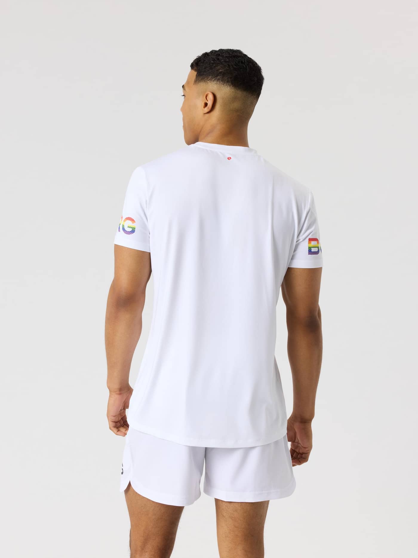Bakifrån på en man i Brilliant White (Vit) Borg T-Shirt med regnbågsfärgade logotyper på ärmarna för träning. - Image 2