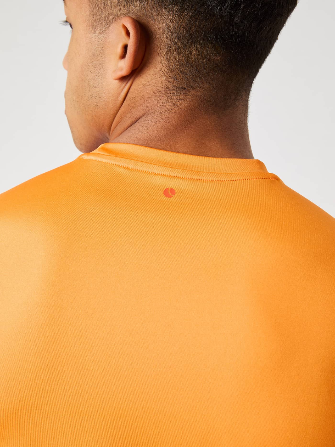 Borg T-Shirt i Sun Orange (Orange) set bagfra i nærbillede med fokus på halskrave og lille logodetalje til træning. - Image 4