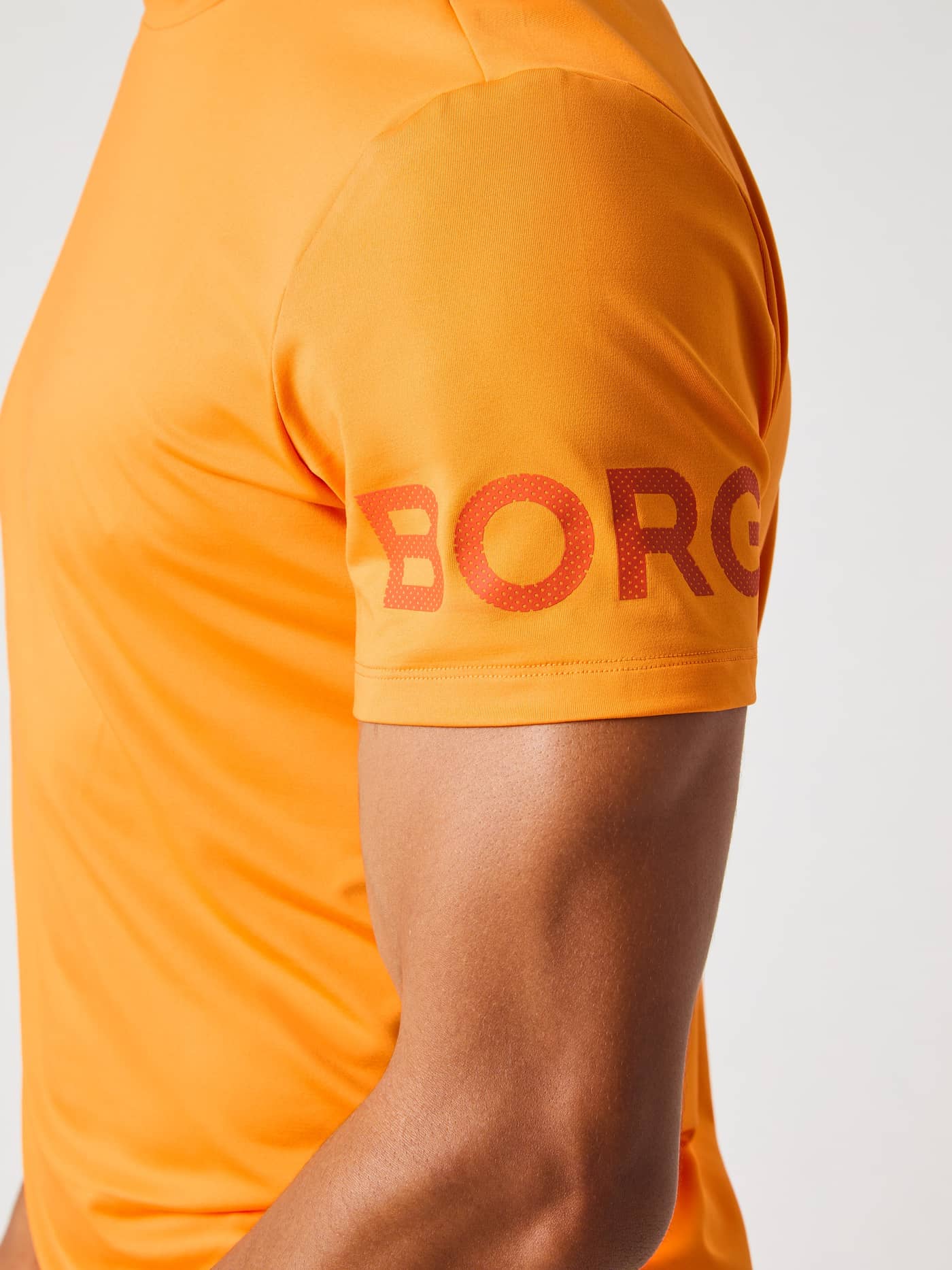 Nærbillede af Borg T-Shirt i Sun Orange (Orange), der viser ærmet med det ikoniske logo til træning. - Image 5