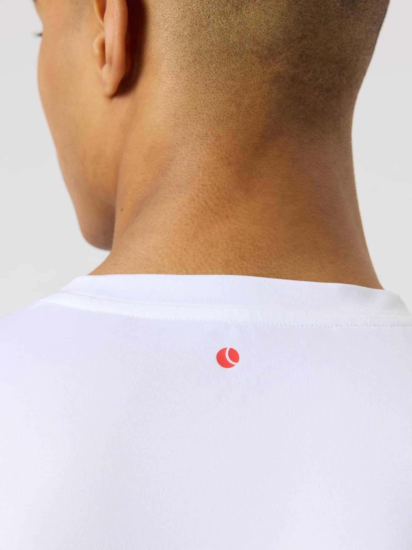 Närbild bakifrån på träningströjan Borg T-Shirt i Brilliant White (Vit) med ett rött tennisbollstryck. - Image 4