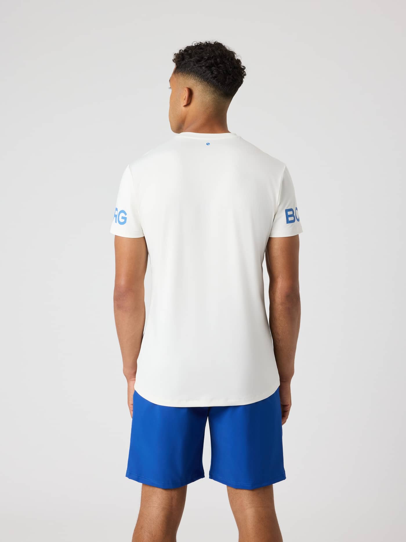 Rückansicht eines Mannes im Borg T-Shirt in Tofu (Weiß) mit blauen Ärmel-Logos für das Training. - Image 2