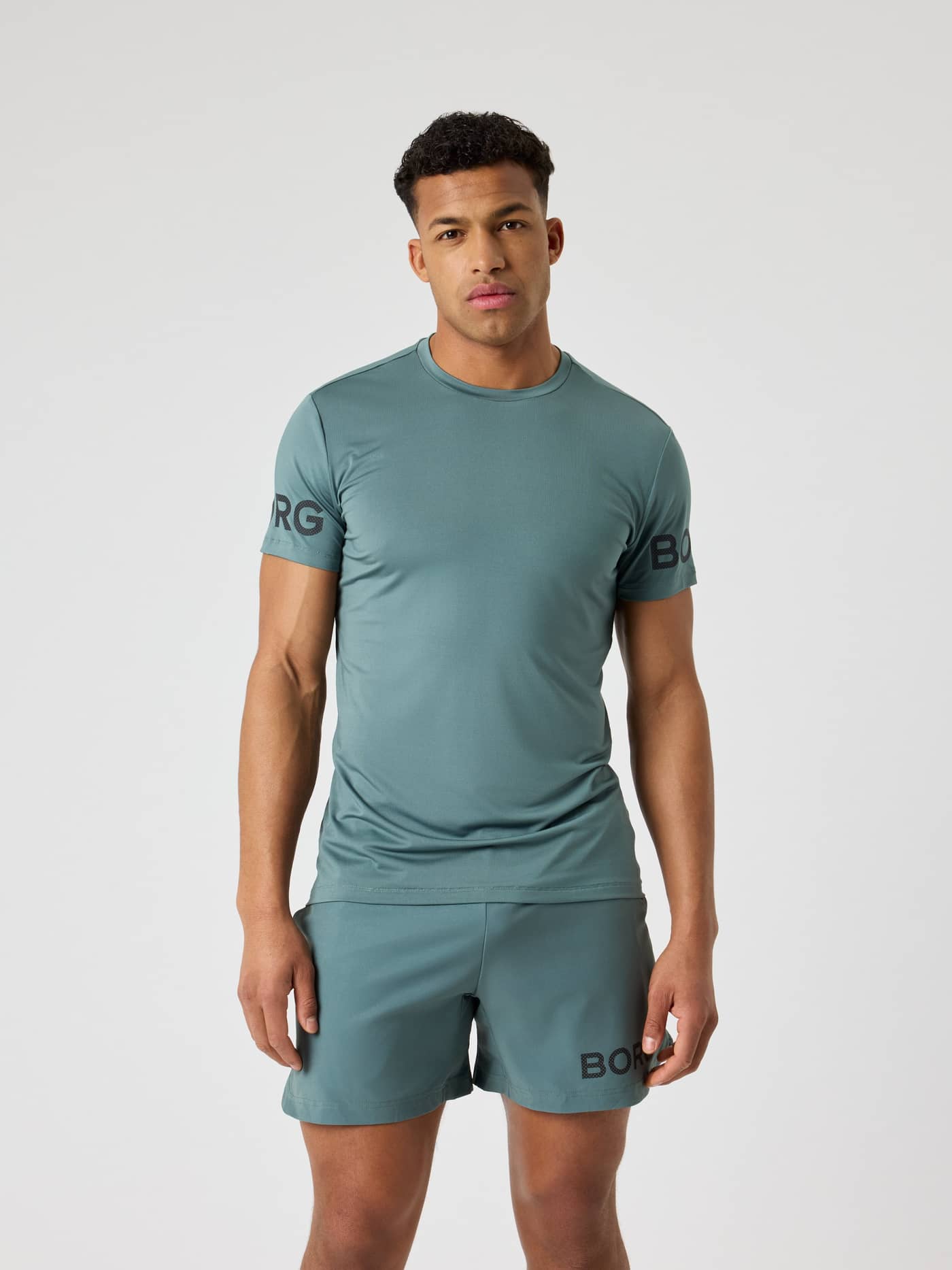 Front view of a man wearing the performance Borg T-Shirt in Balsam Green (Green) with black logos for training. - Image 1