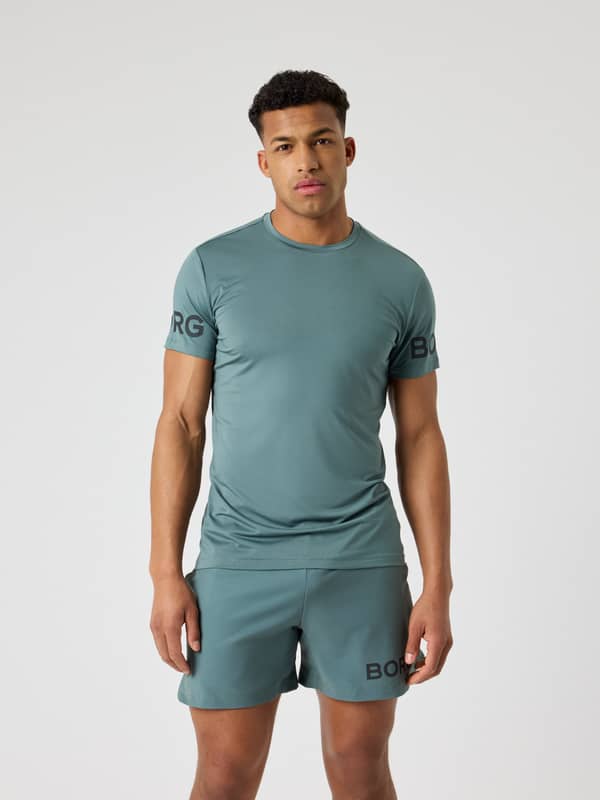 Front view of a man wearing the performance Borg T-Shirt in Balsam Green (Green) with black logos for training.