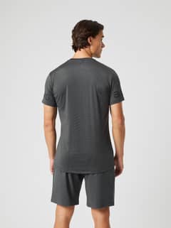 Back view of a man in the asphalt grey Borg T-shirt, featuring a longer back hem and logo on the sleeve. - Image 5