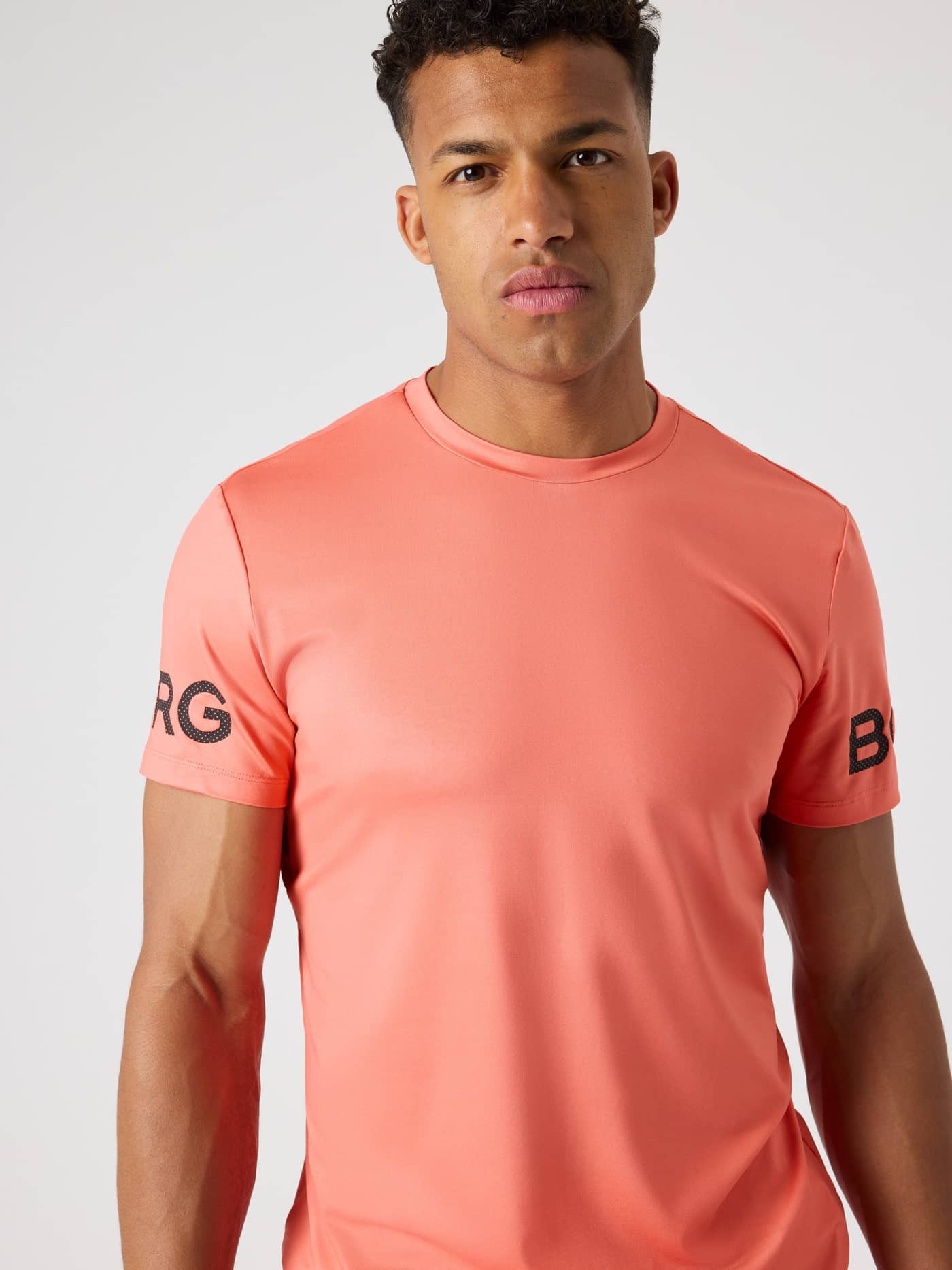 Borg T-Shirt i Coral (Orange) set forfra med sorte logoer, en performance-top ideel til funktionel træning. - Image 4