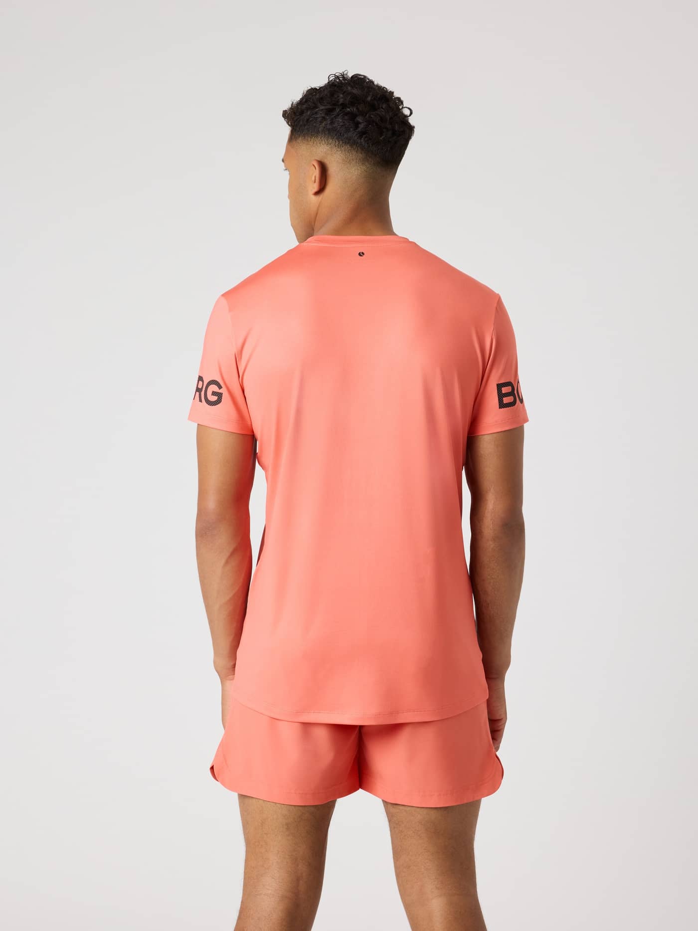 Borg T-Shirt i Coral (Orange) set bagfra med sorte logoer på ærmerne, ideel til funktionel træning. - Image 2