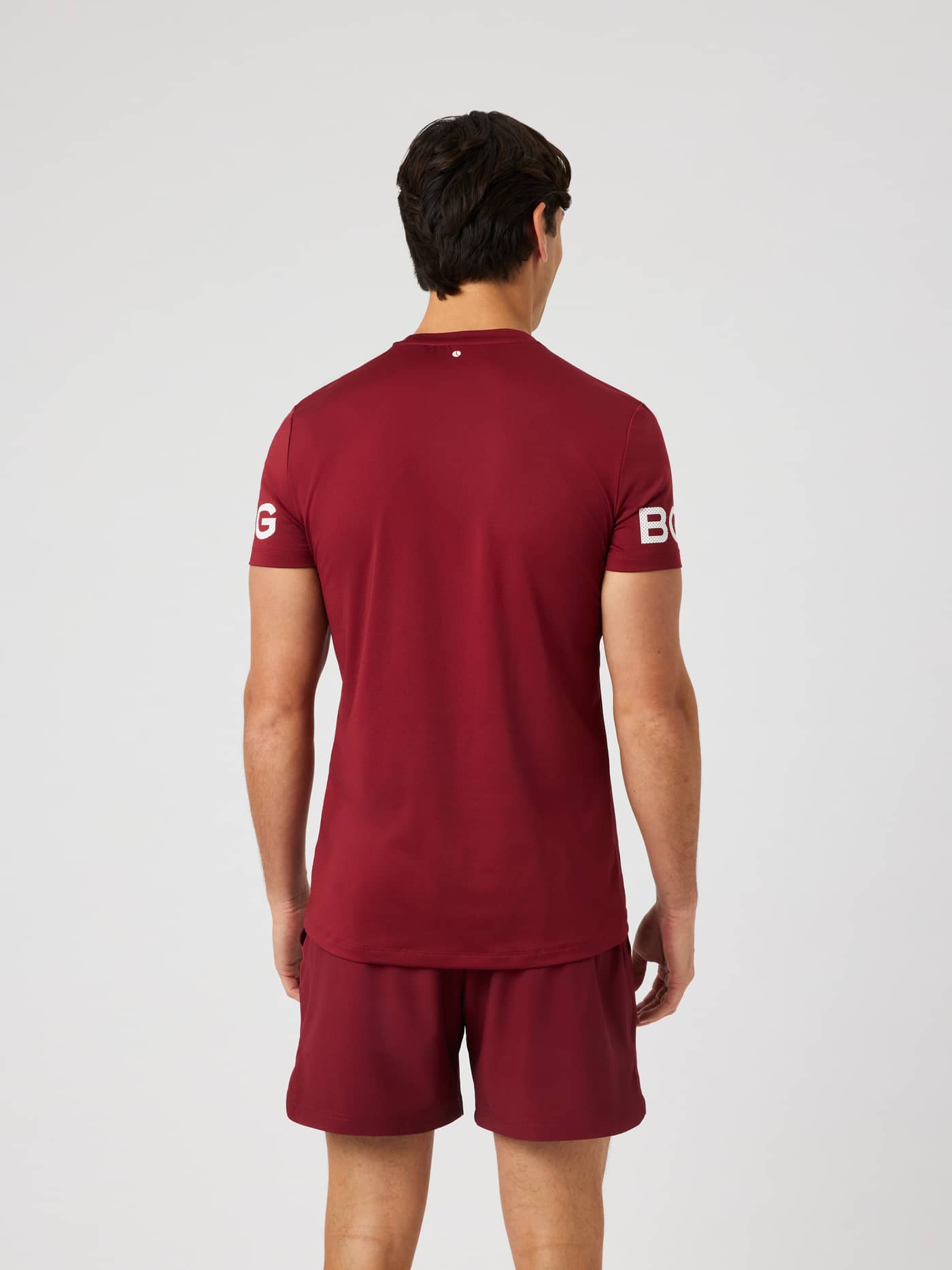 Rear view of the Borg T-Shirt in Cabernet (Red) highlighting the longer back coverage and white arm logo prints for training. - Image 4