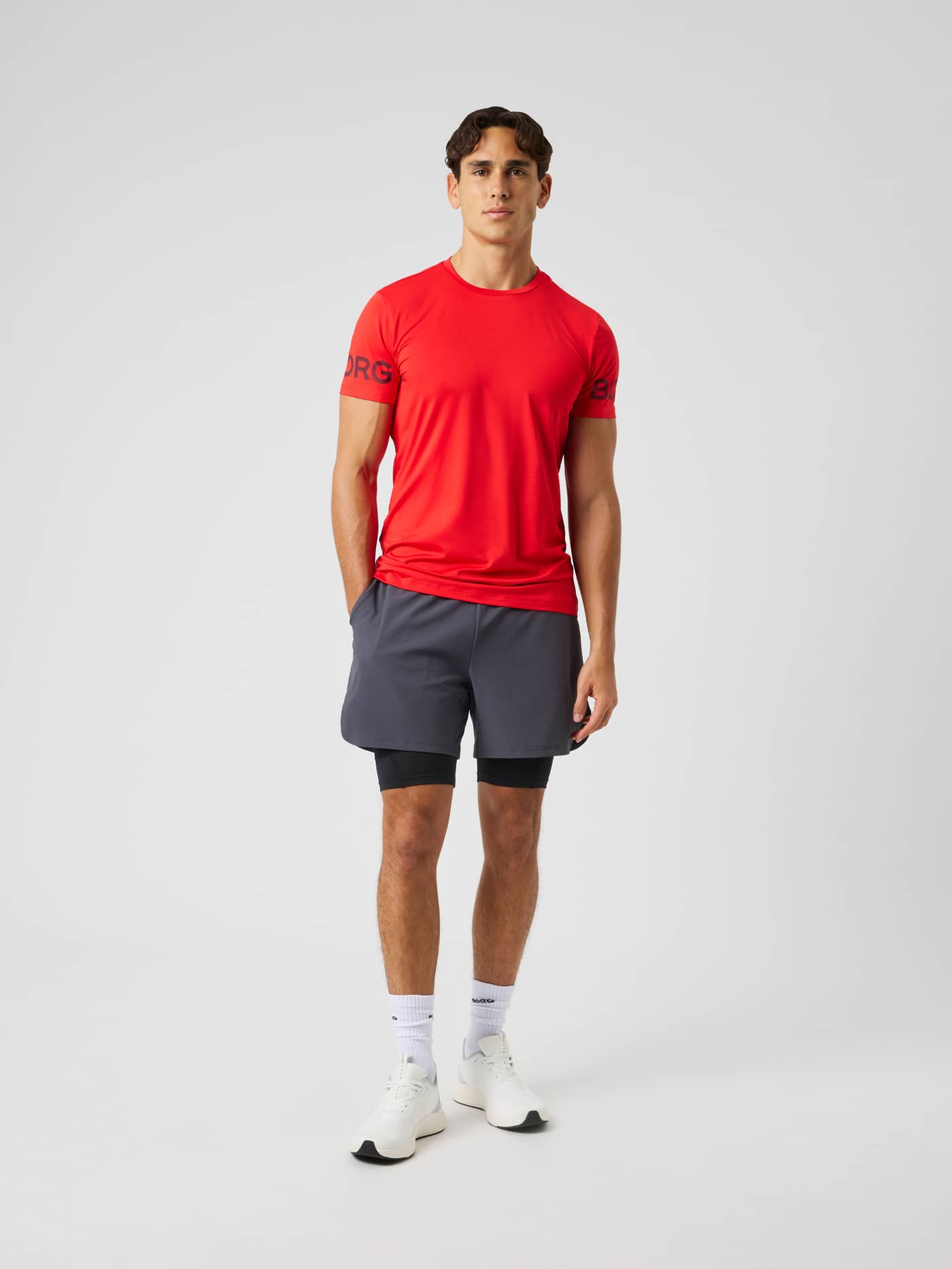 Full-body front view of a model wearing the Borg T-Shirt in Flame Scarlet (Red) with black sleeve logos for training. - Image 4