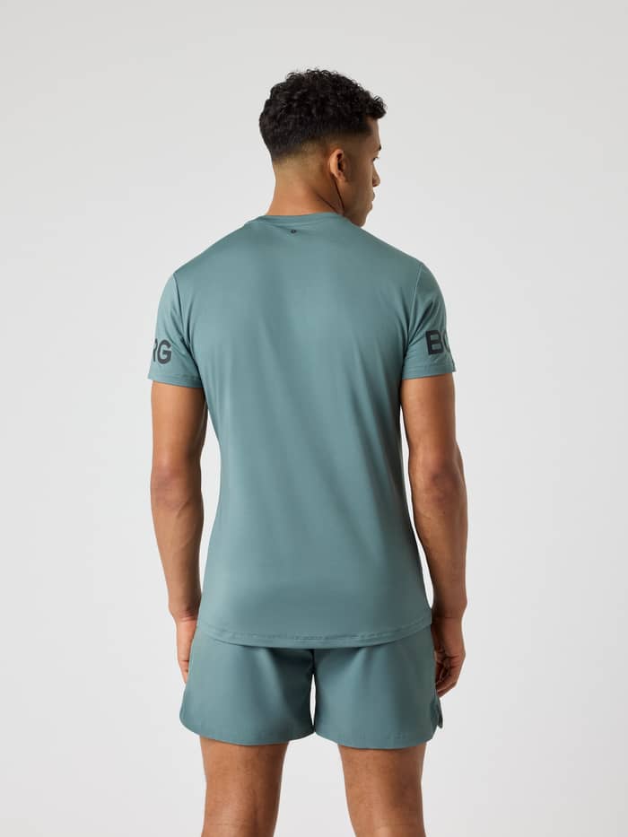 Achteraanzicht van een man in het performance training Borg T-Shirt in Balsam Green (Groen) met mouwlogo's voor tennis. - Image 2