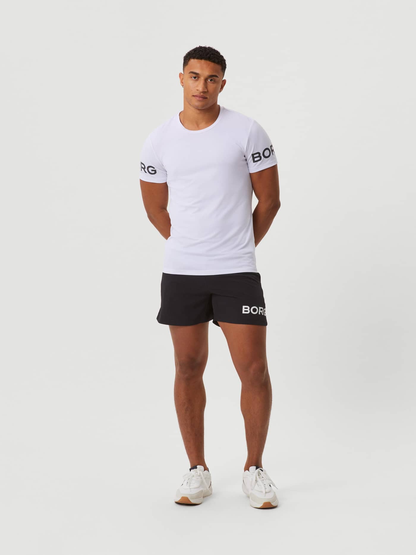 Modell framifrån i Borg T-Shirt i White Black Logo (Vit) med svarta träningsshorts, perfekt för gym och träning. - Image 3