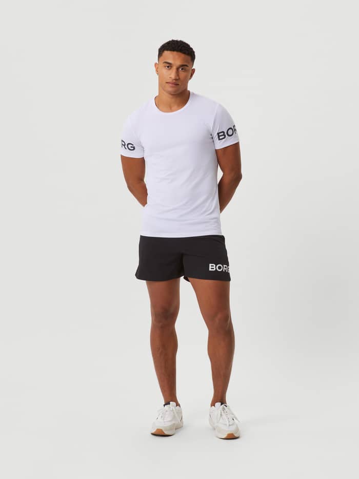 Vorderansicht eines Mannes im Borg T-Shirt in White Black Logo (Weiß) aus recyceltem Polyester mit schwarzen Trainingsshorts. - Image 3