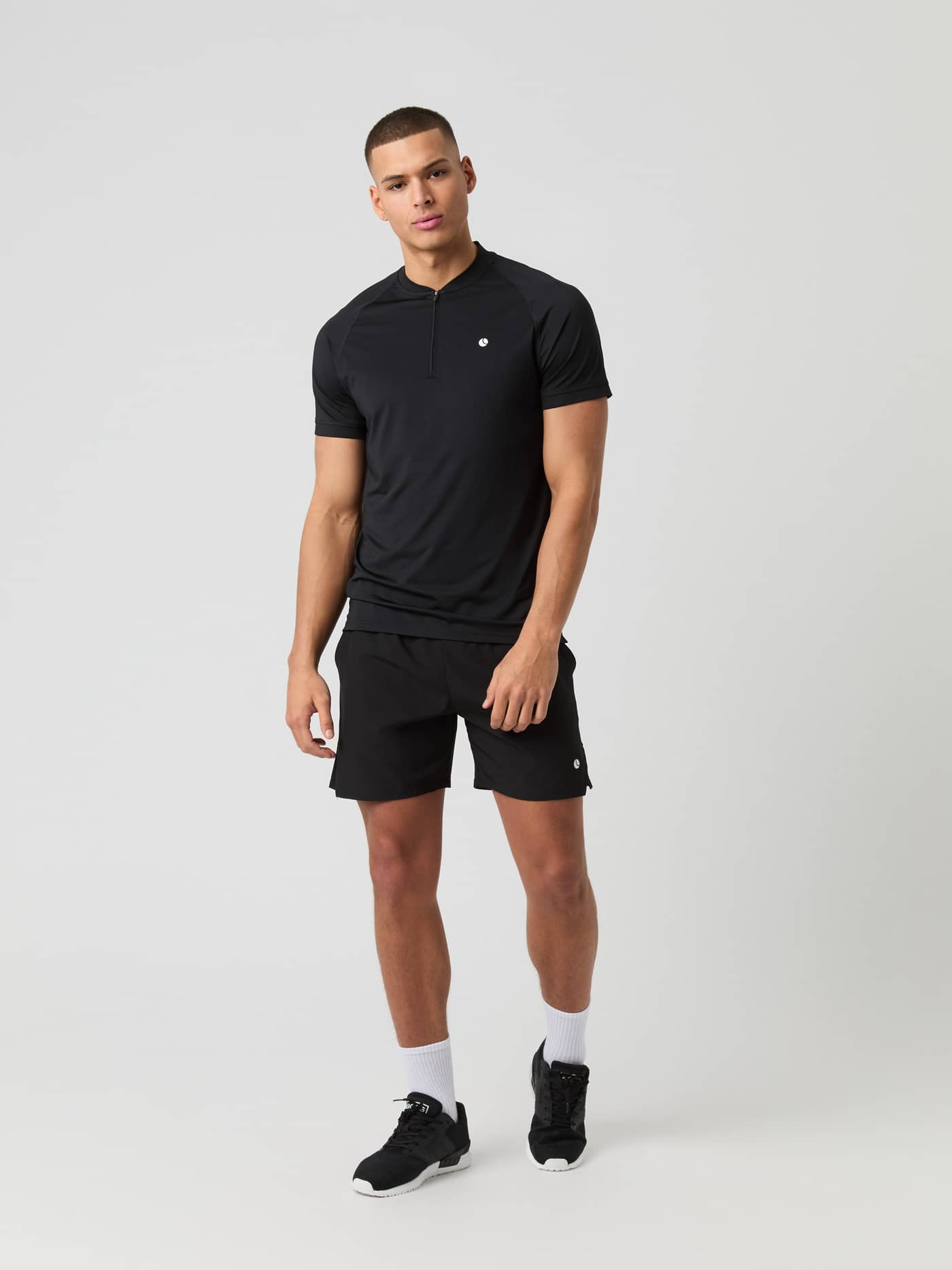 Full-body front view of a man in the Björn Borg Ace Zip Polo Shirt in Black Beauty (Black) for tennis featuring a white logo. - Image 4