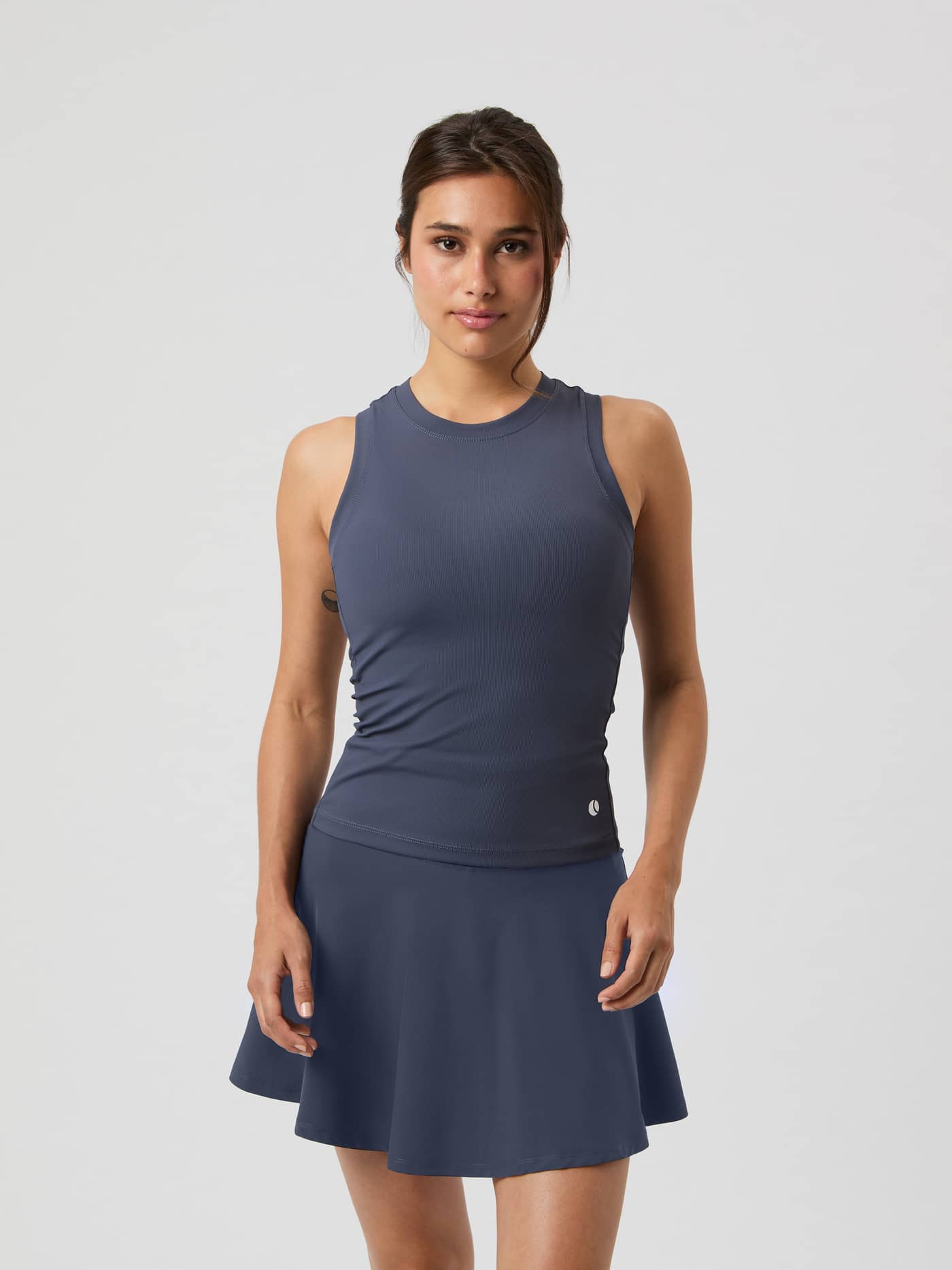 Front view of a model wearing the Björn Borg Ace Pocket Ribbed Tank Top in Odyssey Gray, paired with a matching skirt. - Image 1