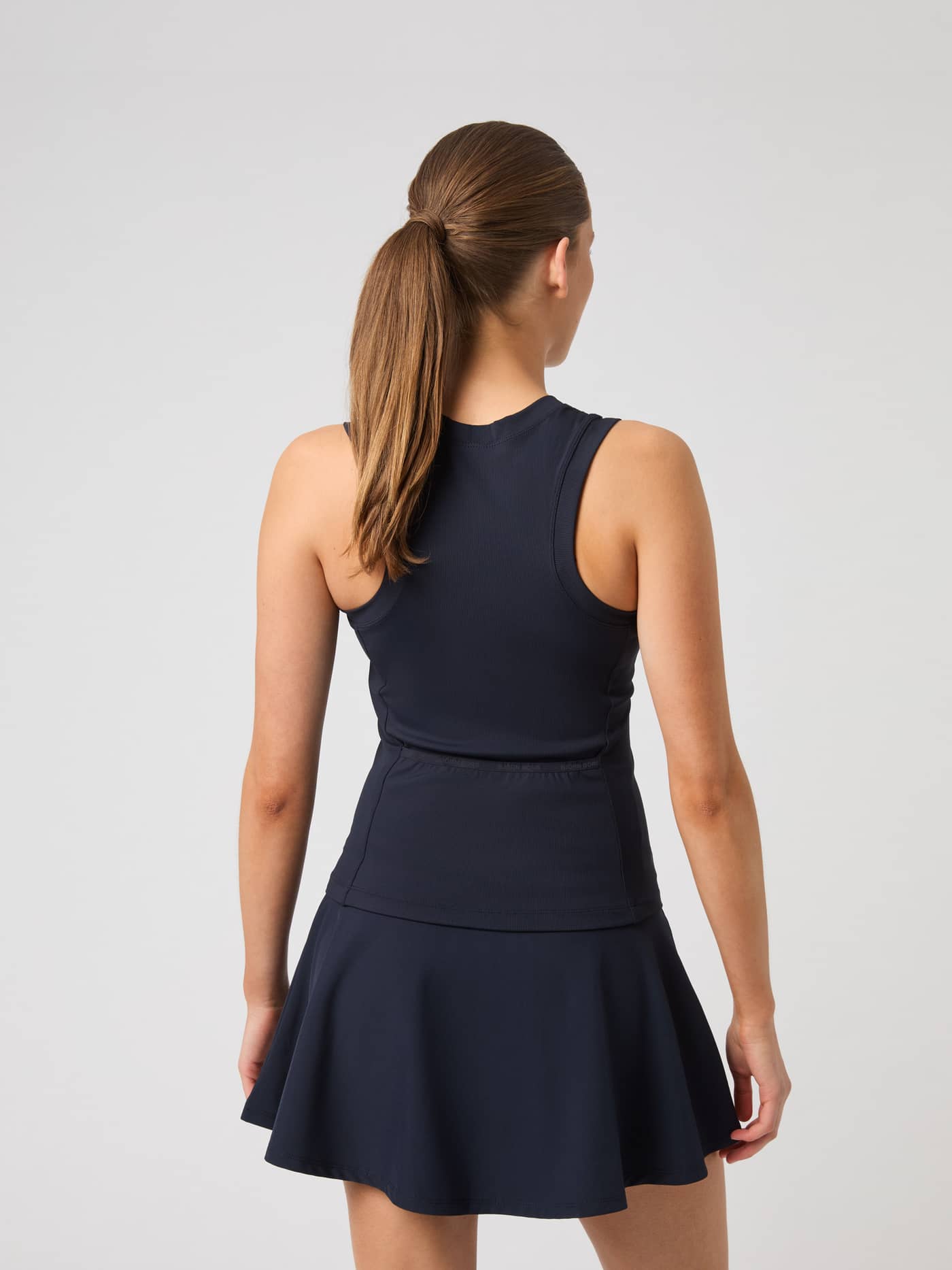 Back view of a model wearing the slim-fit Ace Pocket Ribbed Tank Top in Night sky (Navy), designed for tennis. - Image 2