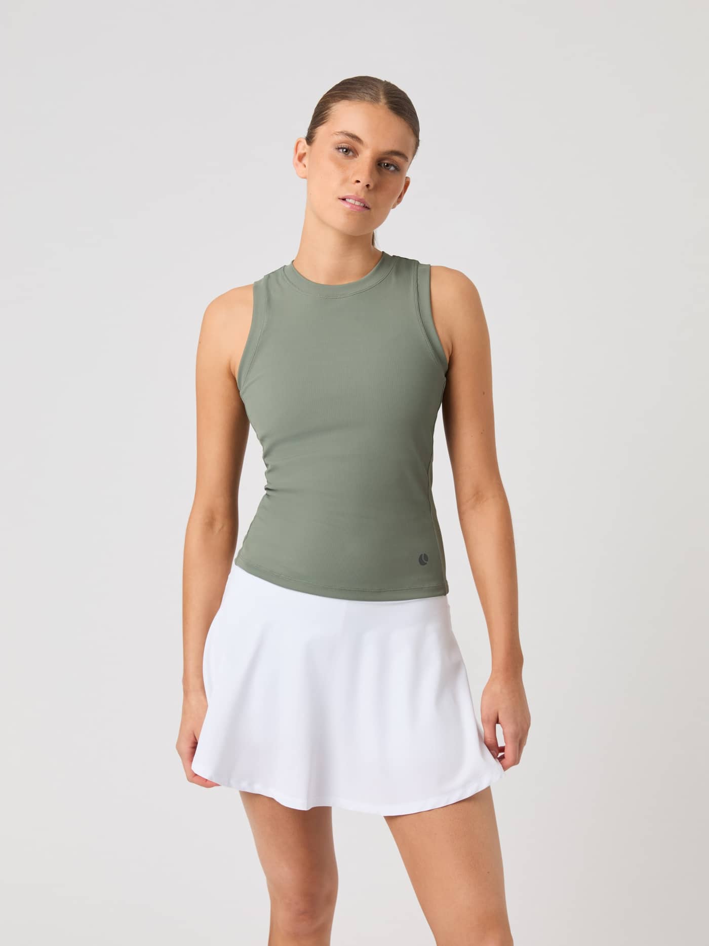 Front view of a model wearing the Björn Borg Ace Pocket Ribbed Tank Top in Agave Green with a white tennis skirt. - Image 1