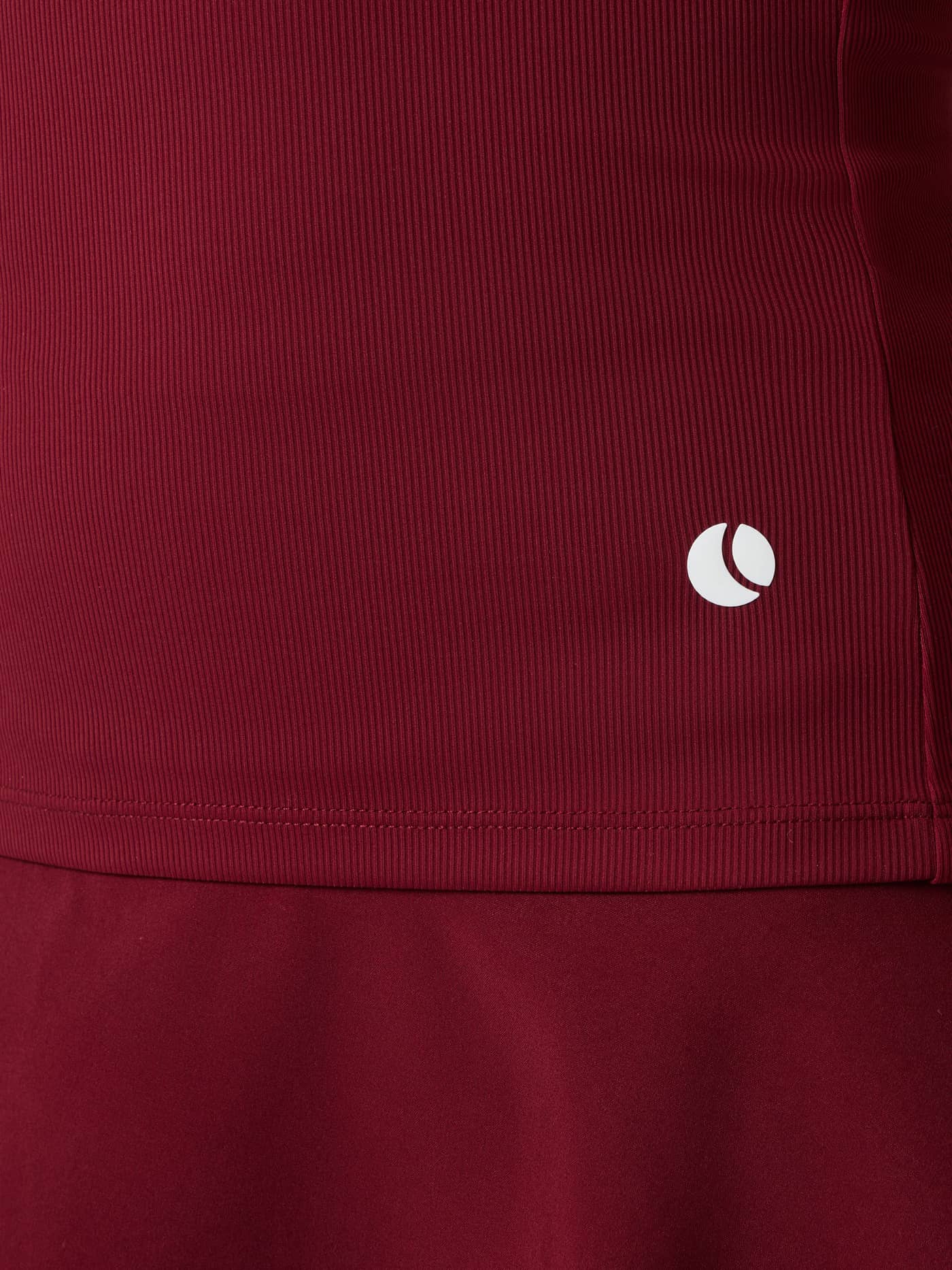 Close-up of the Ace Pocket Ribbed Tank Top in Cabernet (Red) highlighting the white tennis ball logo on the hip. - Image 5