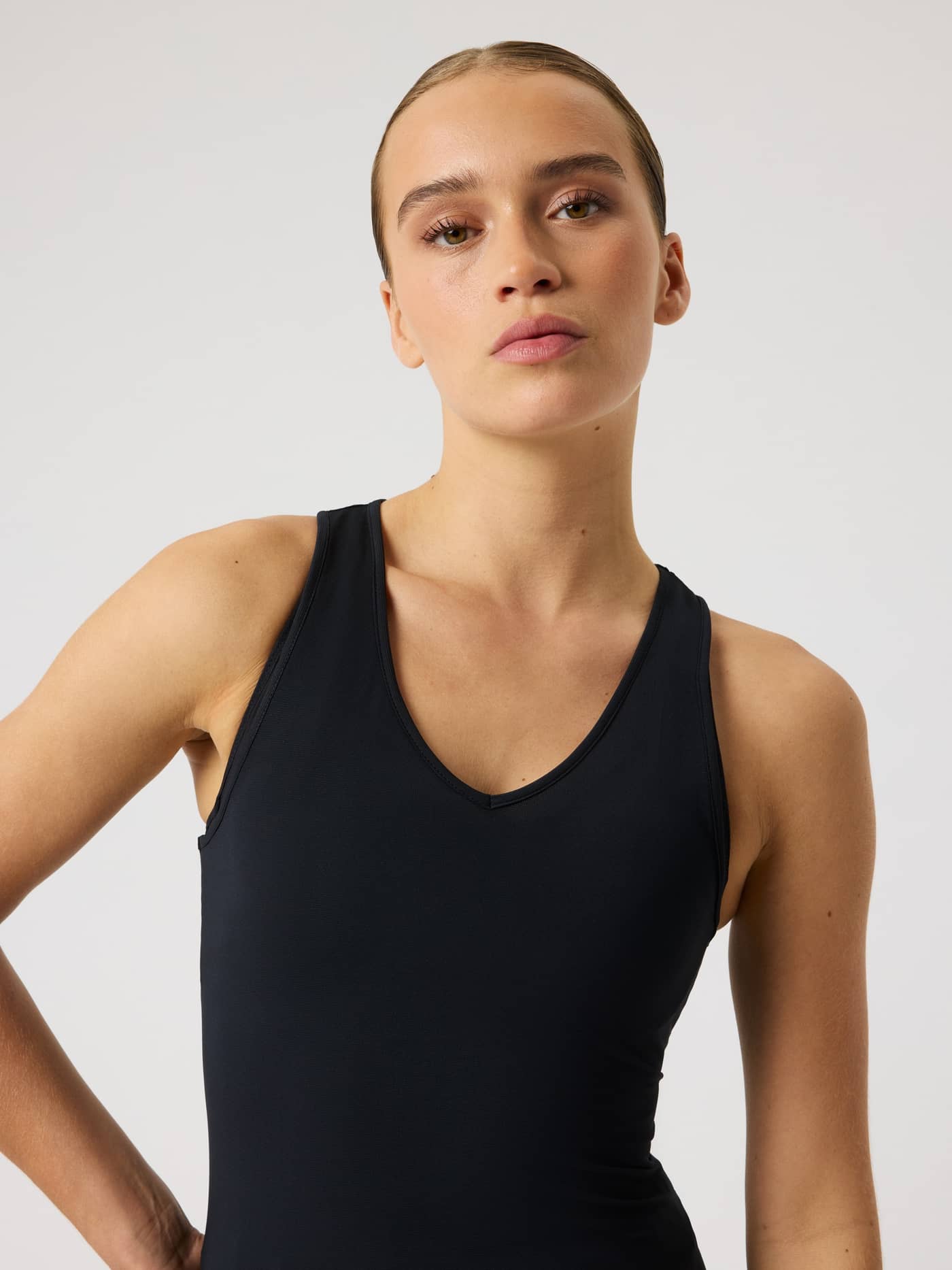 Front view close-up of a woman wearing the slim fit Ace V Neck Tank Top in Black Beauty (Black) for tennis performance. - Image 6