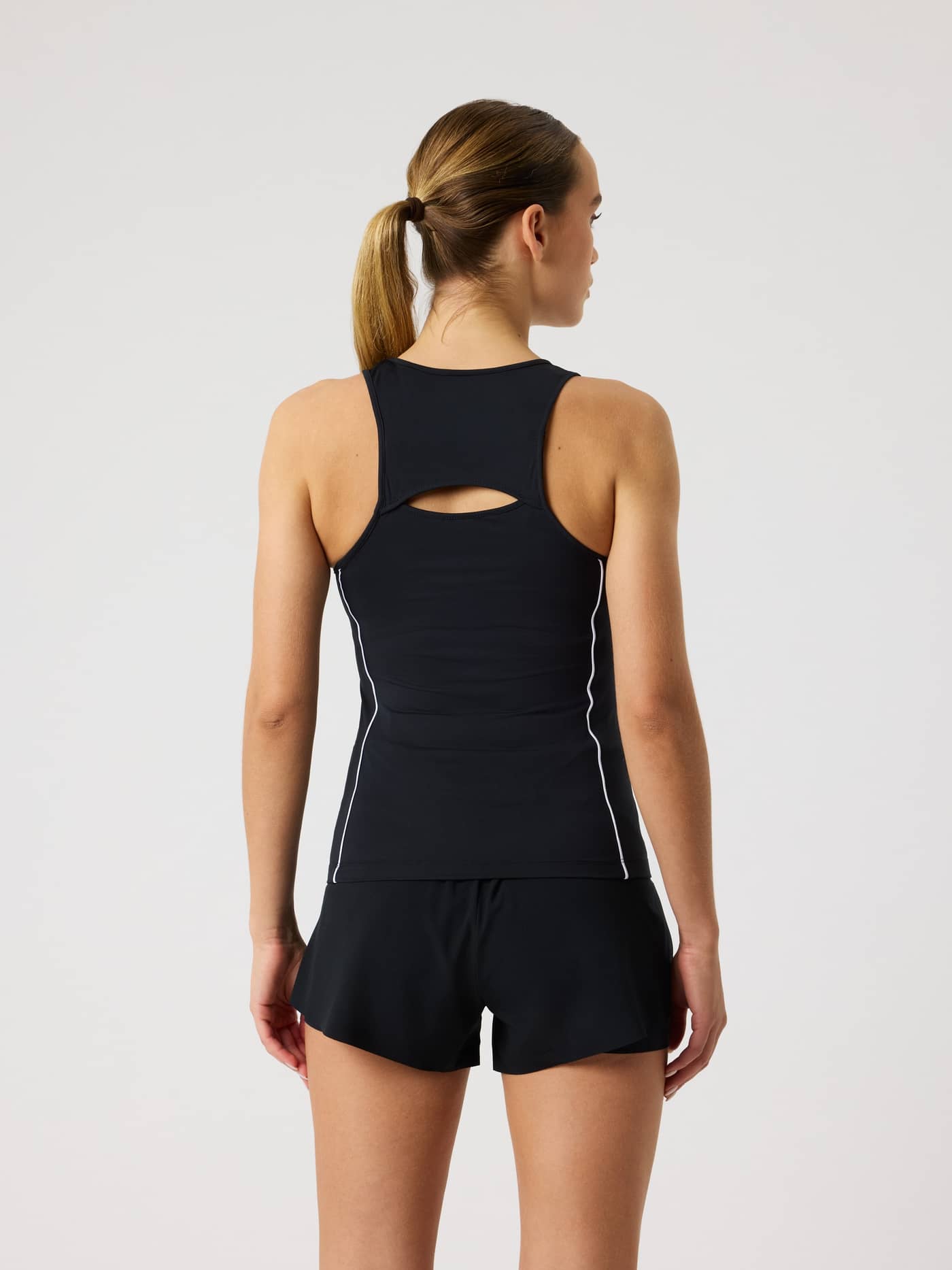Back view of a model in the Ace V Neck Tank Top in Black Beauty (Black), featuring a double-layer open back for tennis. - Image 2