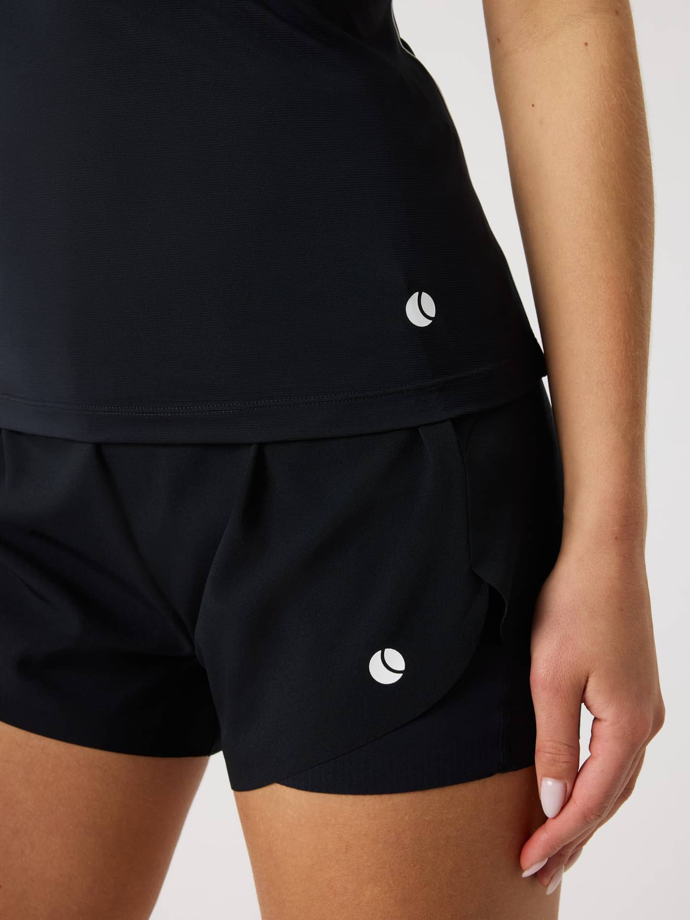 Detailed close-up of the slim fit Ace V Neck Tank Top in Black Beauty (Black) for tennis, with a white tennis ball logo. - Image 5