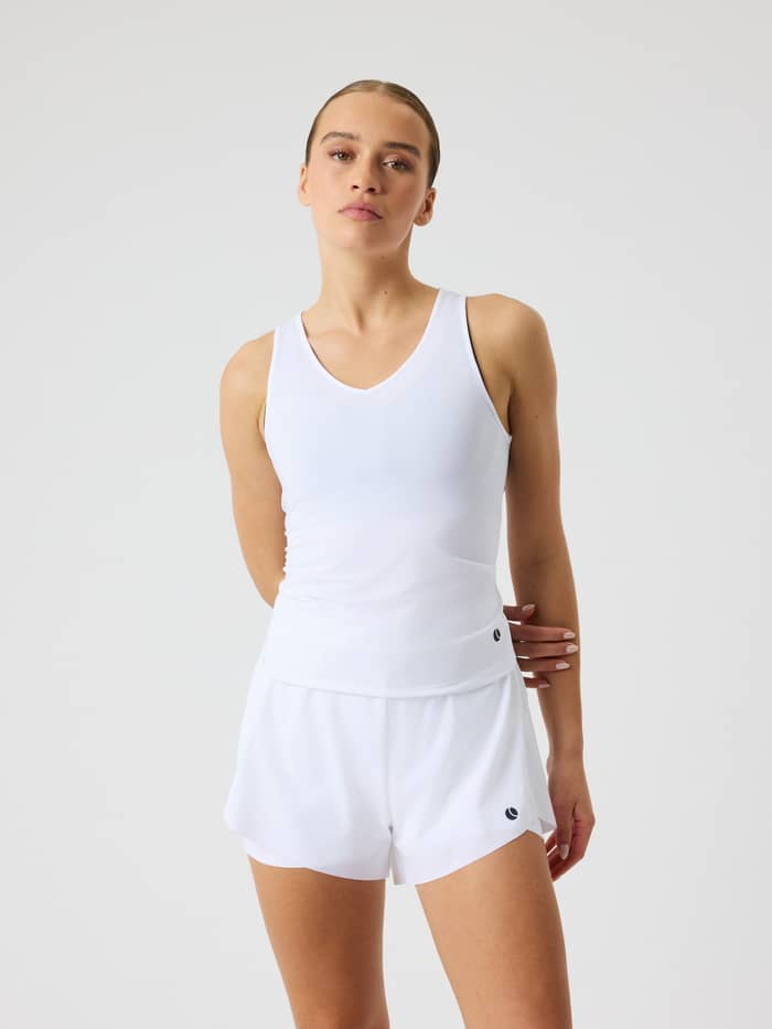 Vooraanzicht van een model in de Ace V Neck Tank Top in Brilliant White (Wit), een slim-fit damestop voor tennis.