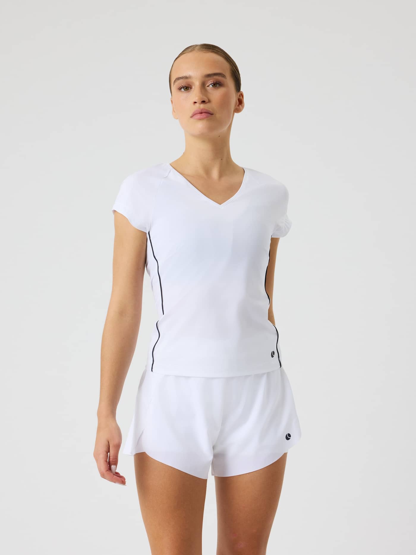 Front view of a woman wearing the slim fit Björn Borg Ace V-Neck T-Shirt in Brilliant White (White) for tennis. - Image 1