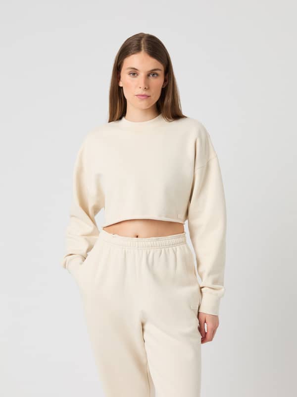 Front view of a woman wearing the Björn Borg Studio Oversized Cropped Sweatshirt in Birch (White) with a cropped fit.