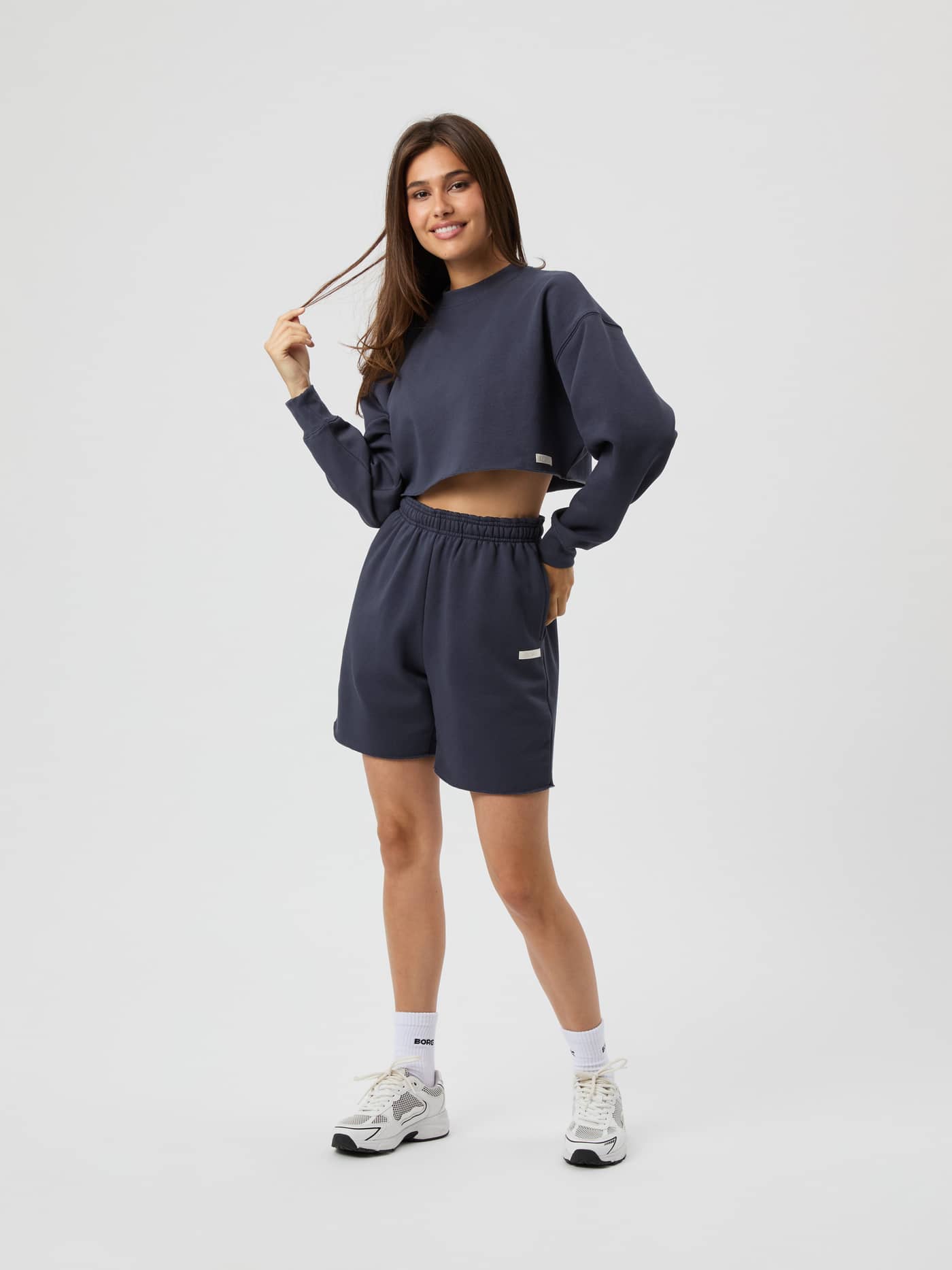 Front view of a woman wearing the Studio Oversized Cropped Sweatshirt in Odyssey Gray (Grey) with a white logo for training. - Image 4