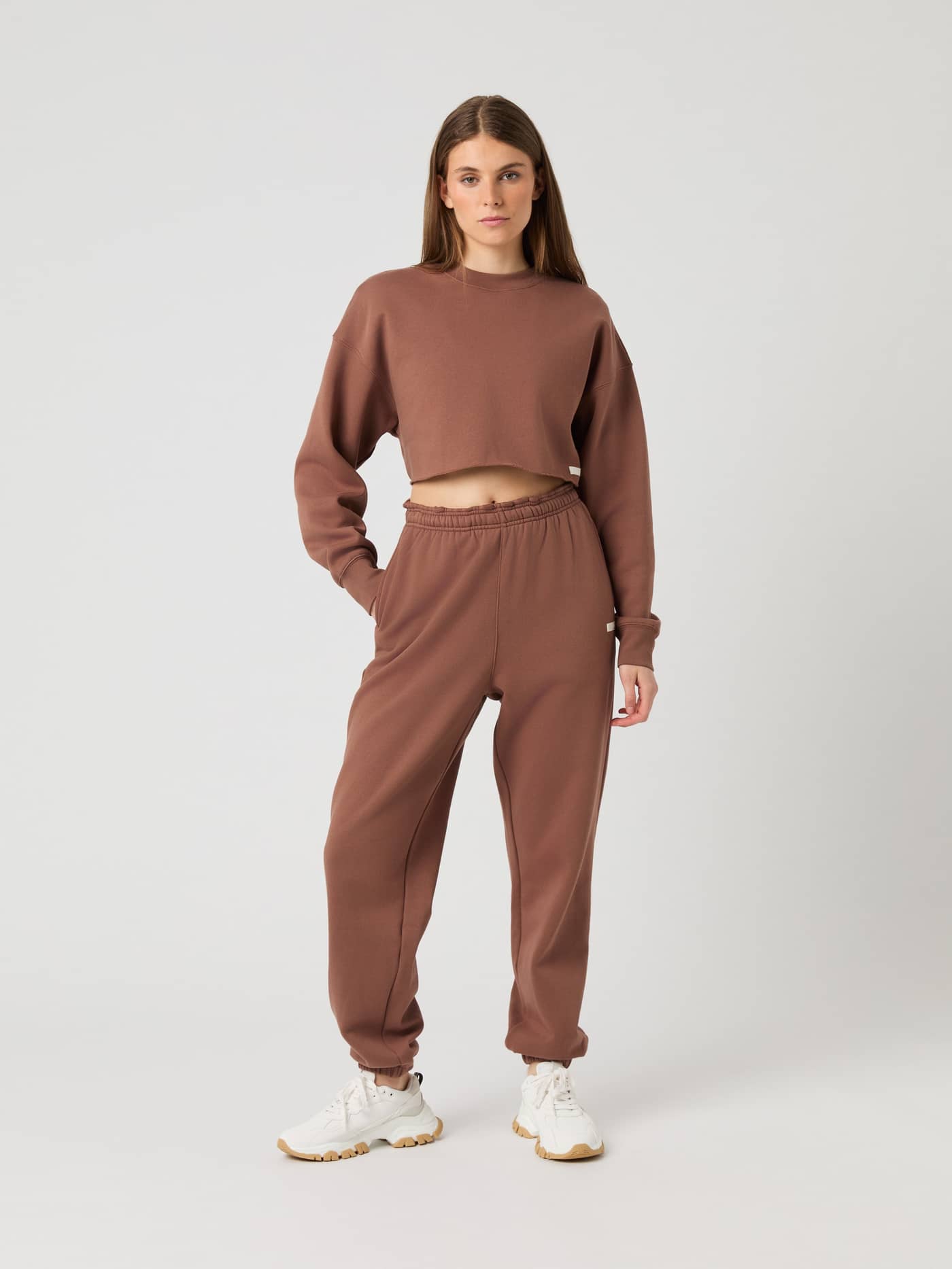 Full-body front view of a model in Acorn (Brown) Studio Oversized Cropped Sweatshirt with white logo for training and fit. - Image 3
