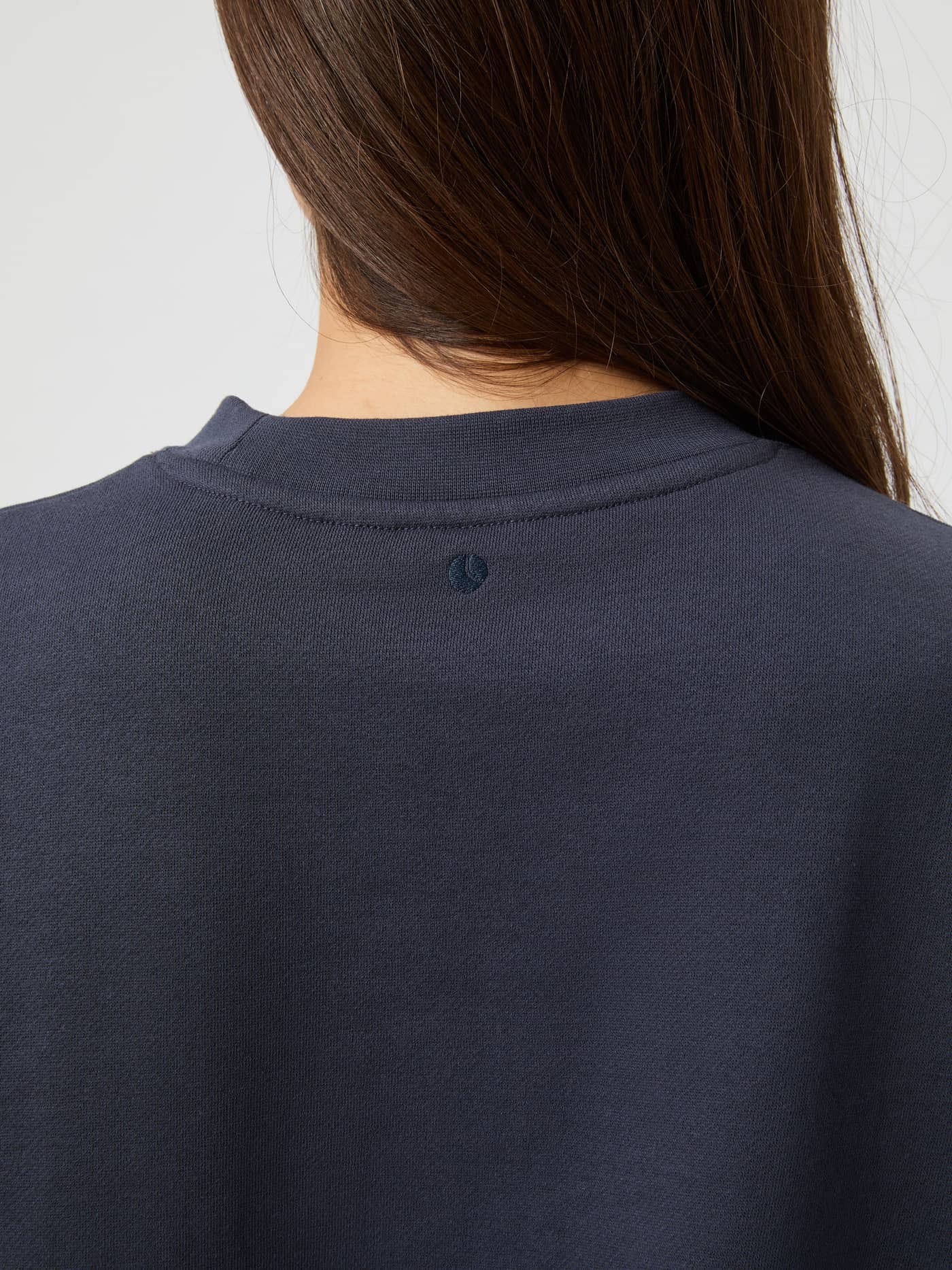 Close-up back view of the Studio Oversized Cropped Sweatshirt in Odyssey Gray (Grey) showing the small neckline logo. - Image 5