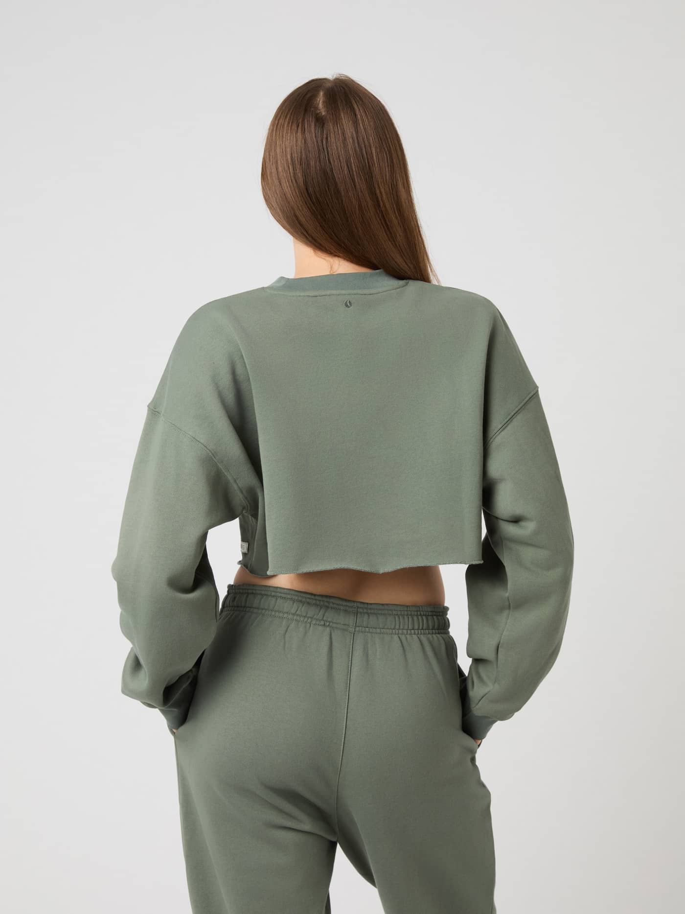 Back view of a woman wearing the Studio Oversized Cropped Sweatshirt in Agave Green (Green) with a relaxed training fit. - Image 4