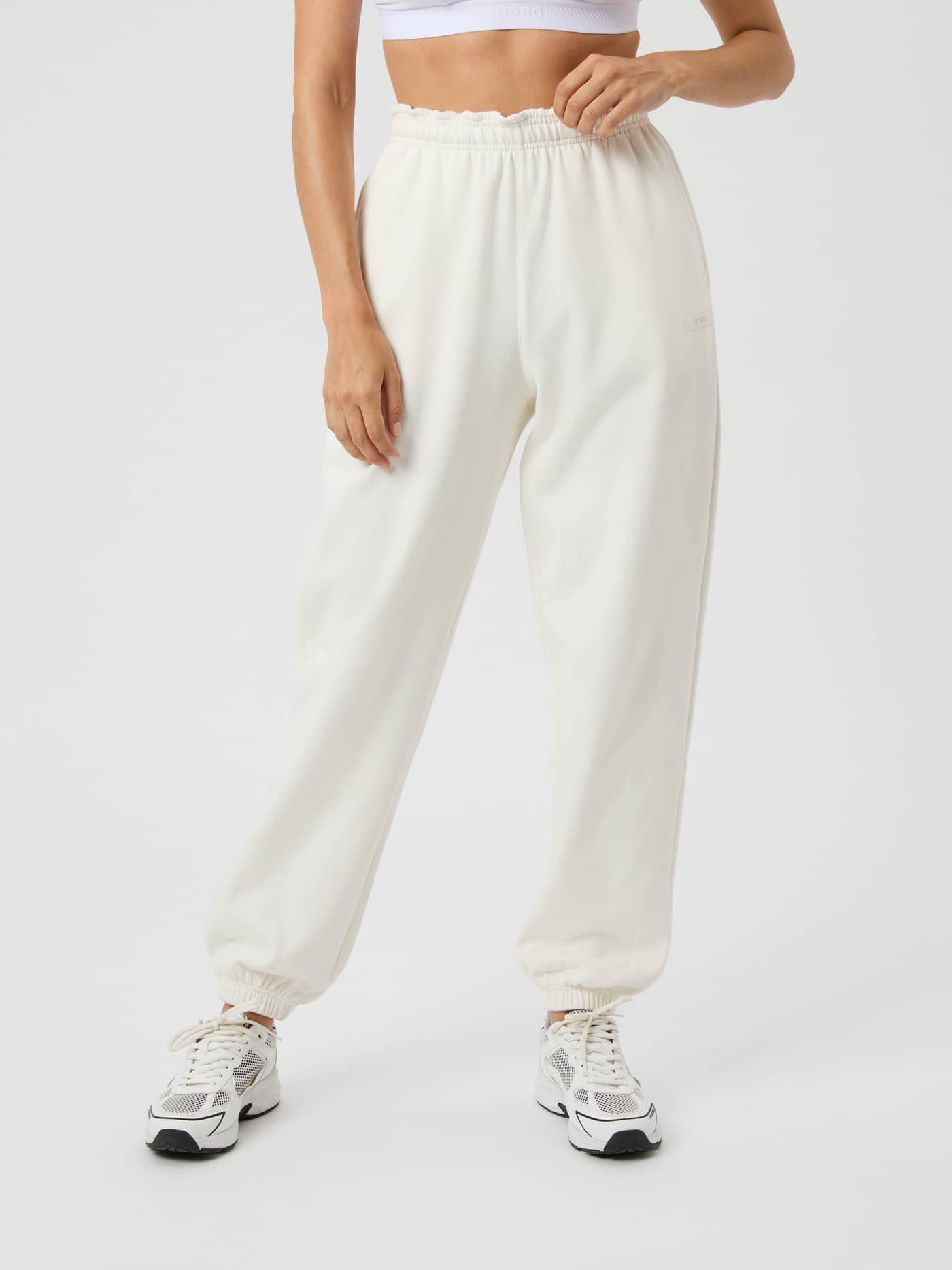 Front view of a model wearing the Björn Borg Studio Oversized Sweatpants in Cannoli Cream (White) with a high waist. - Image 2
