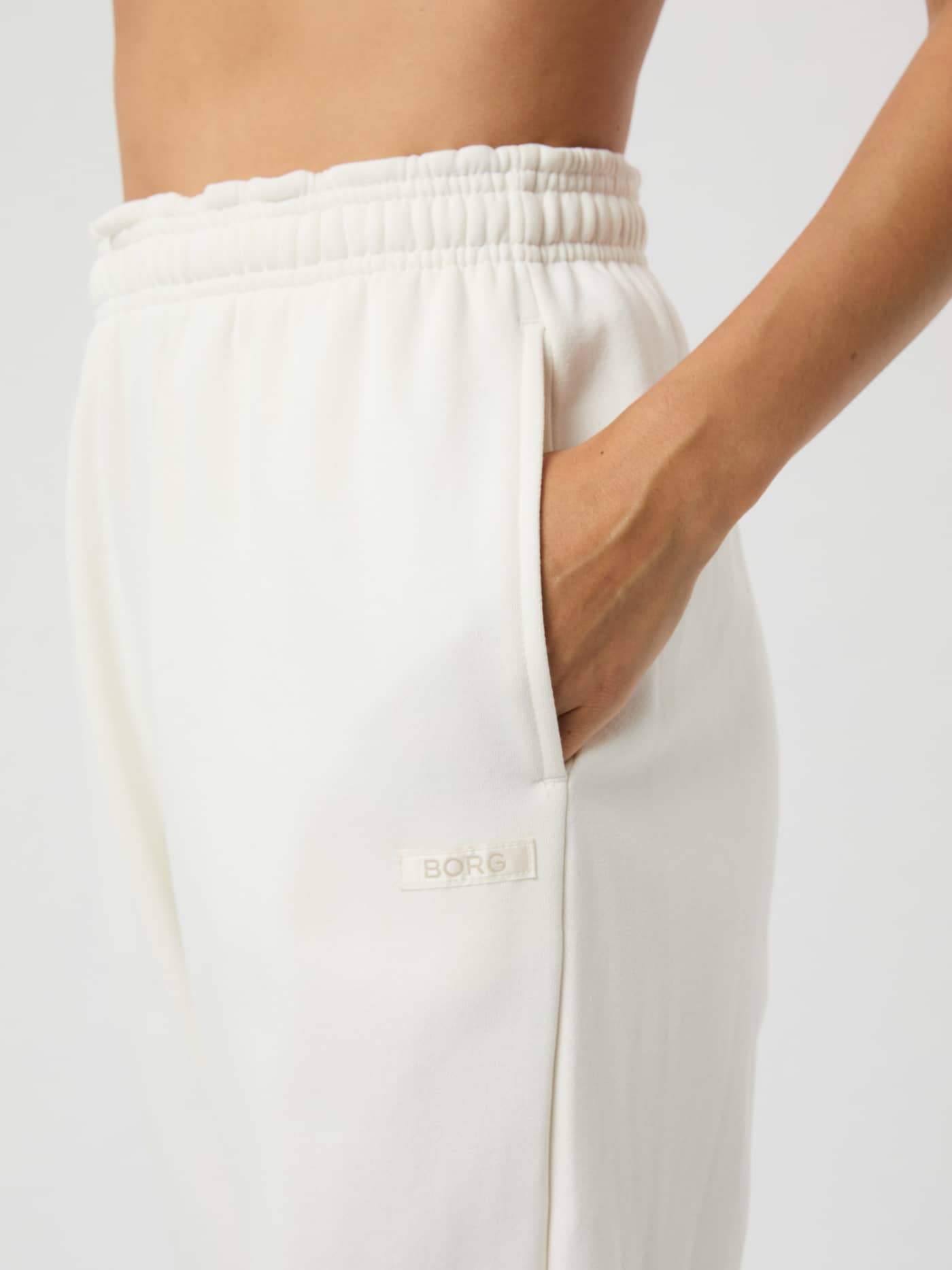 Close-up of Studio Oversized Sweatpants in Cannoli Cream (White) with a ribbed waistband and cream satin BORG logo. - Image 4