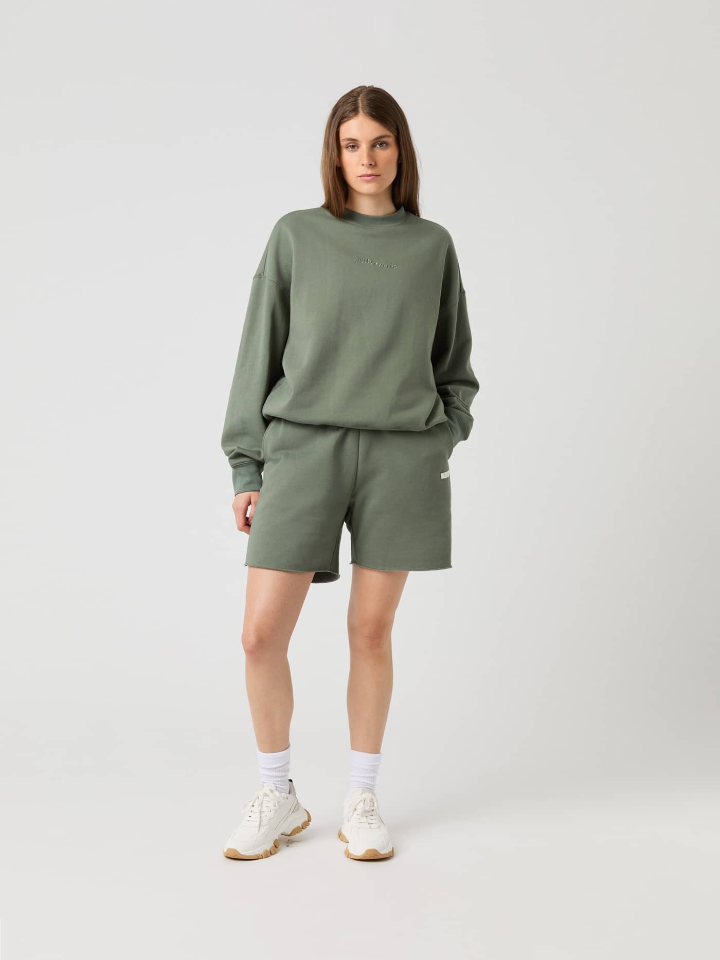 Full-body front view of a woman wearing the oversized Björn Borg Studio Oversized Sweatshorts in Agave Green (Green). - Image 1