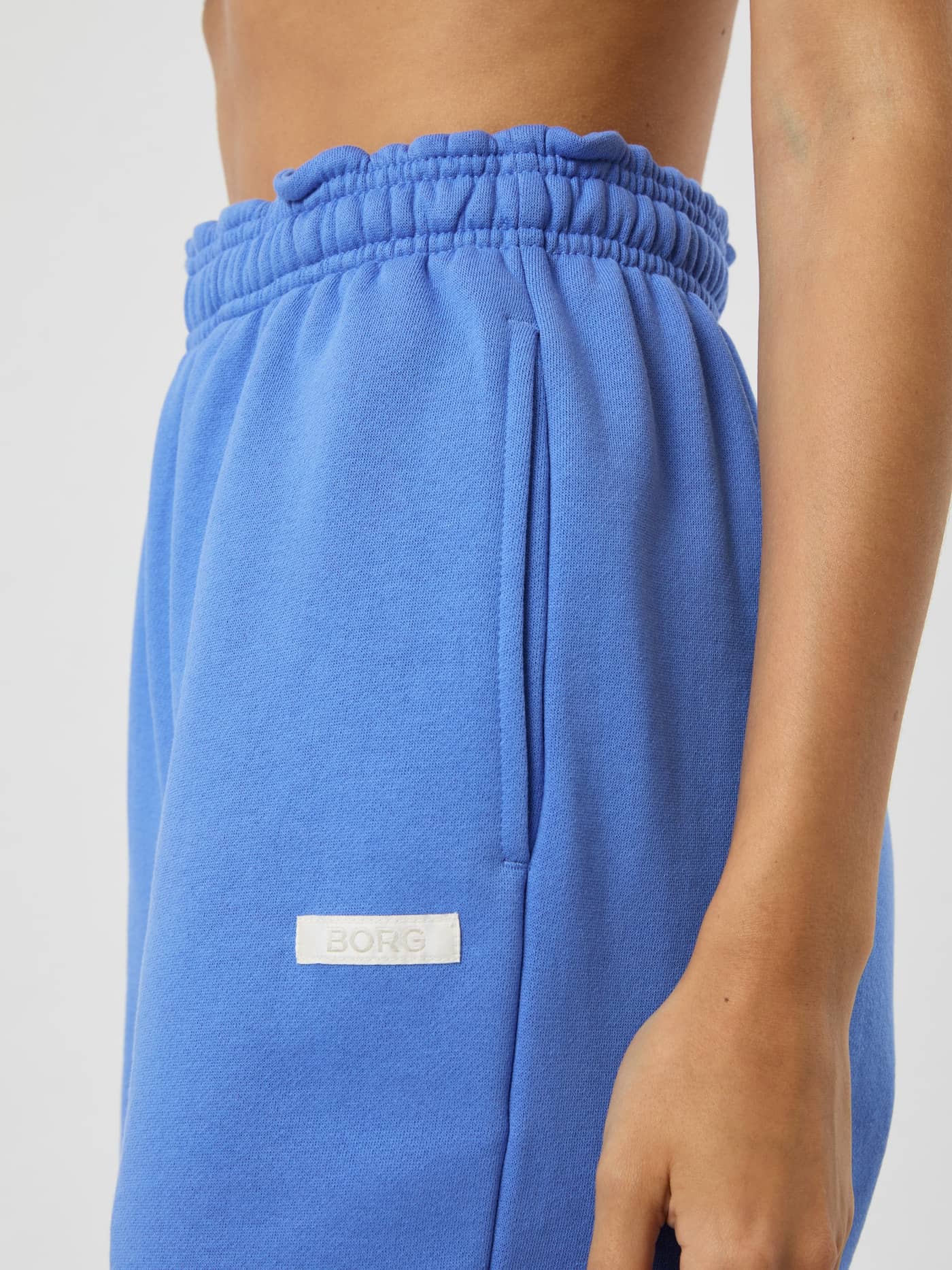 Detailed side view of the fleece Studio Oversized Sweatshorts in Ultramarine (Blue) for women's training, with a white logo. - Image 6