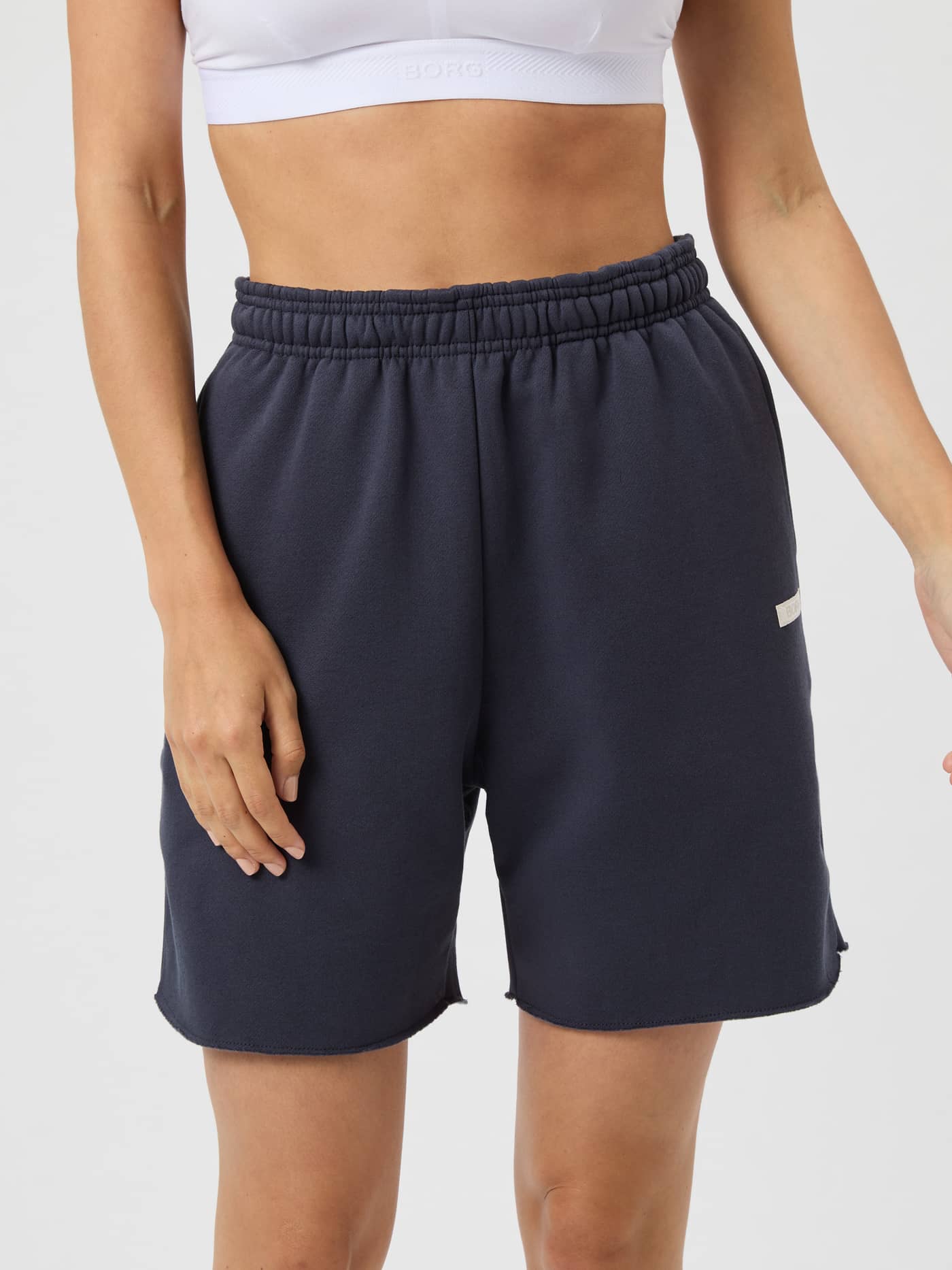 Studio Oversized Sweatshorts i Odyssey Gray (Grå) sett forfra på kvinne, fleece, hvit logo, stilfull og avslappet passform. - Image 2